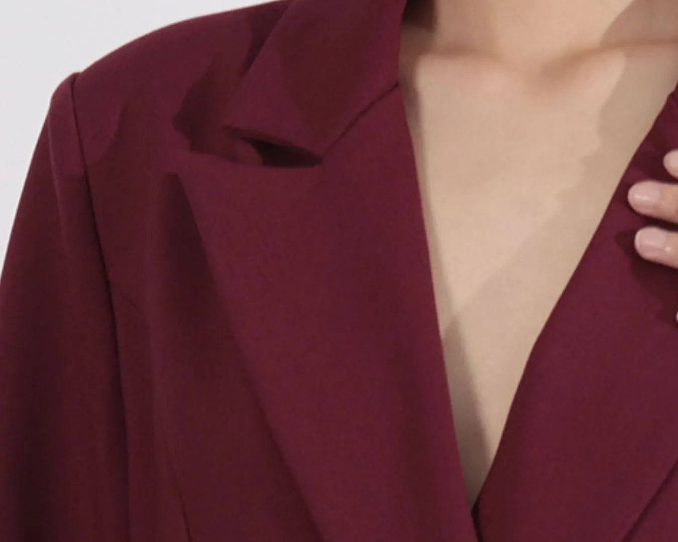 NEWYORKLISTED Runway Style: Close-up of a burgundy blazer worn by a person on a white background