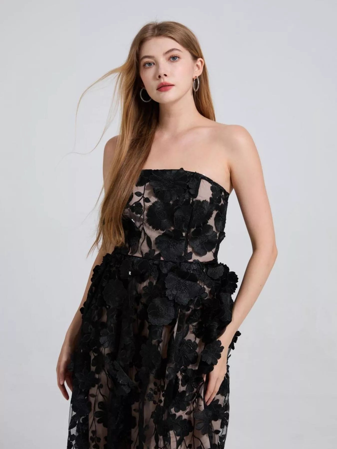 NEWYORKLISTED STYLE COLLECTION: Woman wearing a black strapless dress with floral details on a white background
