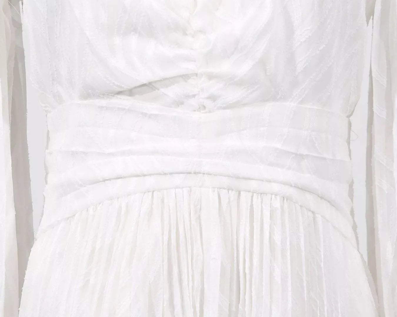 NEWYORKLISTED STYLE COLLECTION: Close-up of a white dress with a textured fabric and pleated design.