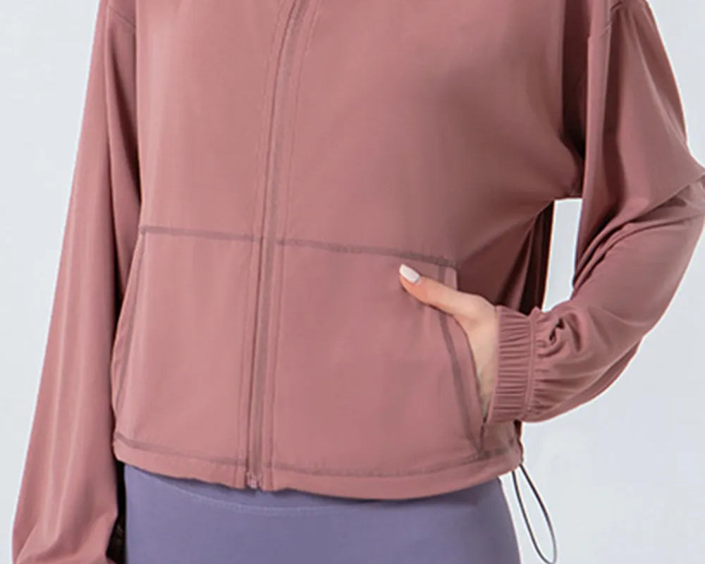NEWYORKLISTED ACTIVEWEAR COLLECTION: Person wearing a pink jacket and purple leggings on a light gray background