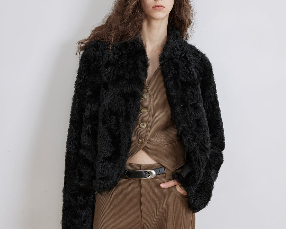 NEWYORKLISTED STYLE COLLECTION: Woman wearing a black fur jacket and brown pants against a white background