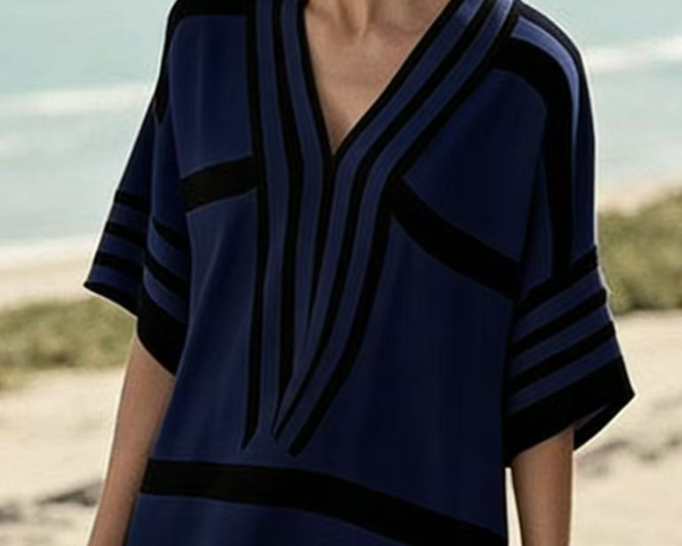 NEWYORKLISTED STYLE COLLECTION: Woman wearing a blue and black patterned dress on a beach.