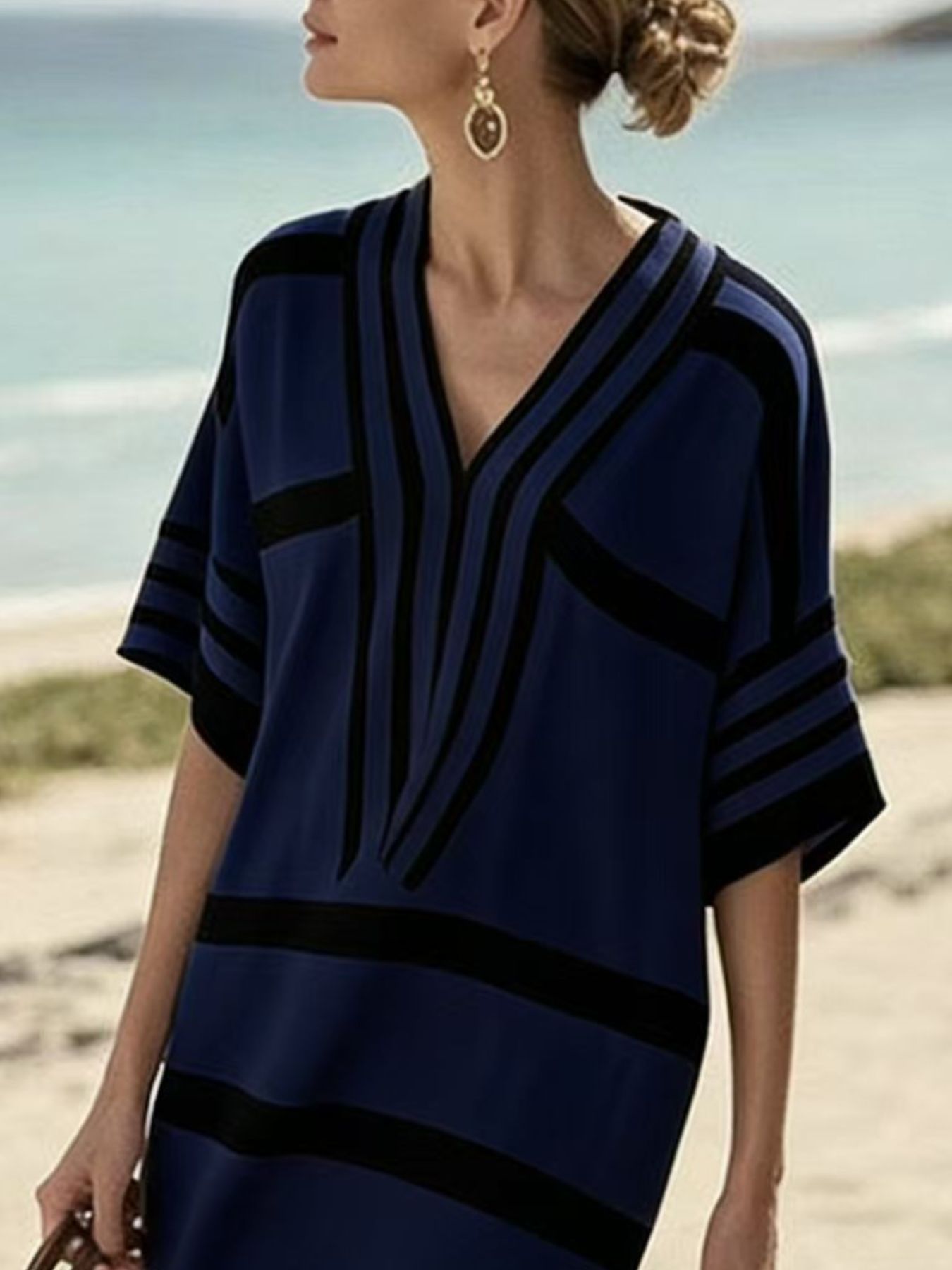 NEWYORKLISTED STYLE COLLECTION: Woman wearing a blue and black patterned dress on a beach.
