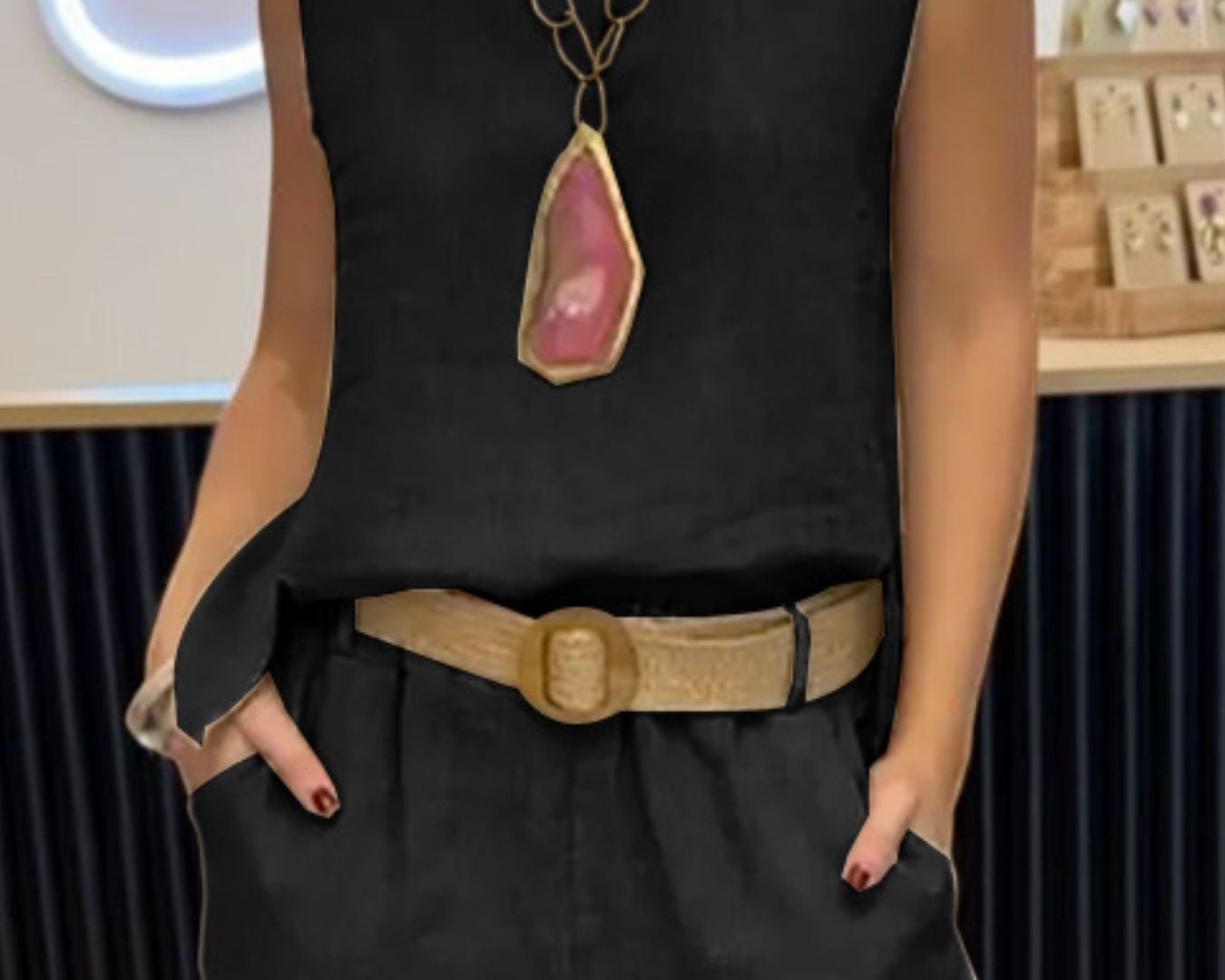 NEWYORKLISTED COMFORT COLLECTION: Person wearing a black sleeveless top with a large pendant necklace and high-waisted black pants.
