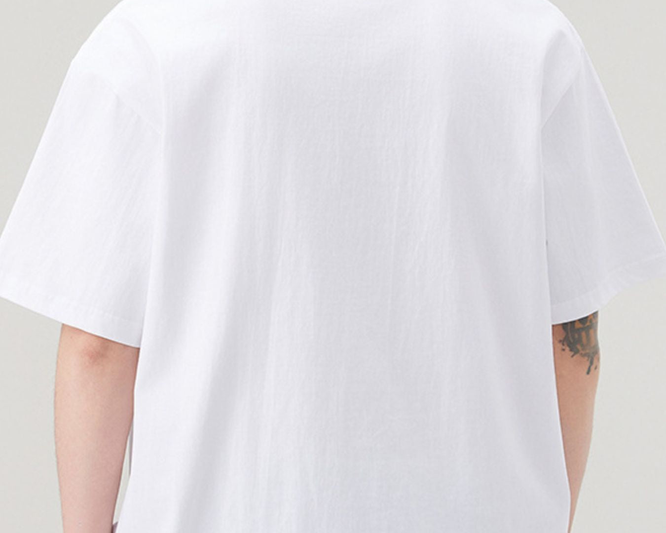 Person wearing a plain white t-shirt against a neutral background
