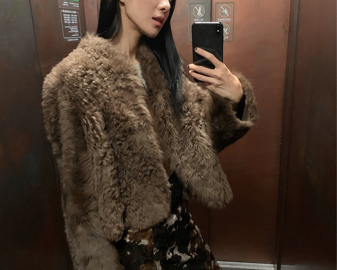 NEWYORKLISTED STYLE COLLECTION: Person wearing a fluffy brown coat taking a mirror selfie in an elevator.