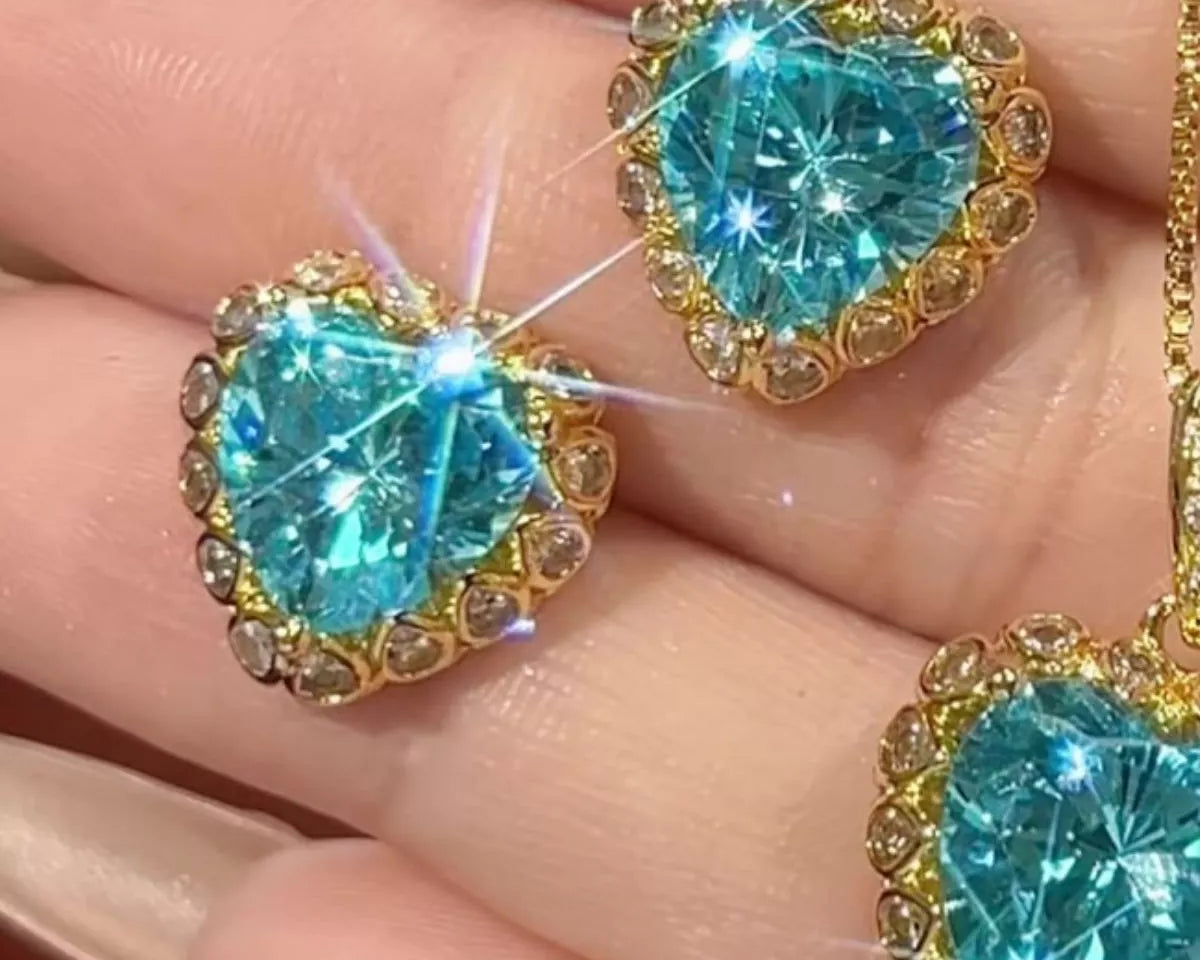 NYLD Glamour Collection by NEWYORKLISTED: Turquoise heart-shaped gemstones in gold settings held between fingers.