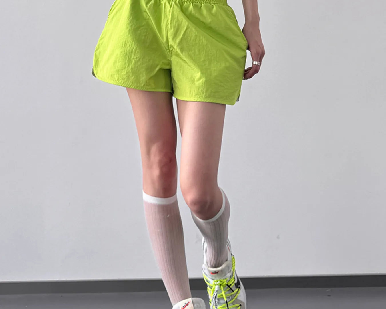 NEWYORKLISTED ACTIVEWEAR: Person wearing bright green shorts and shoes on a plain background