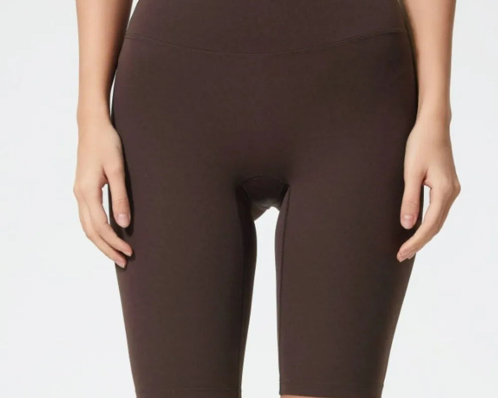 Person wearing brown high-waisted shorts on a plain background