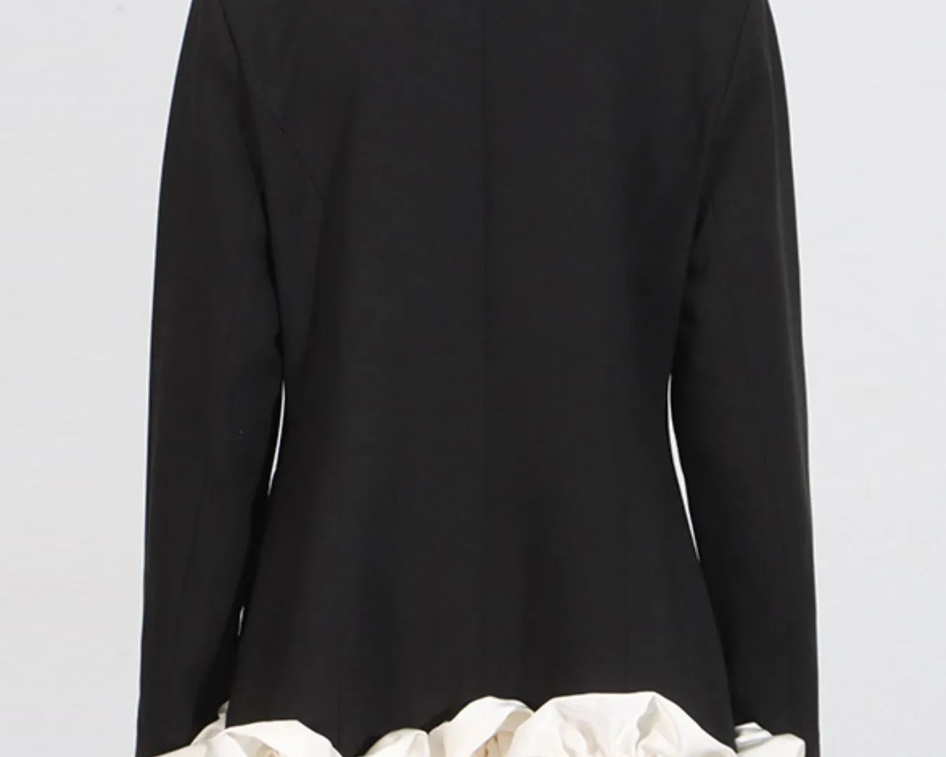 NEWYORKLISTED Runway Style: Black coat with white ruffled hem on a mannequin against a light gray background