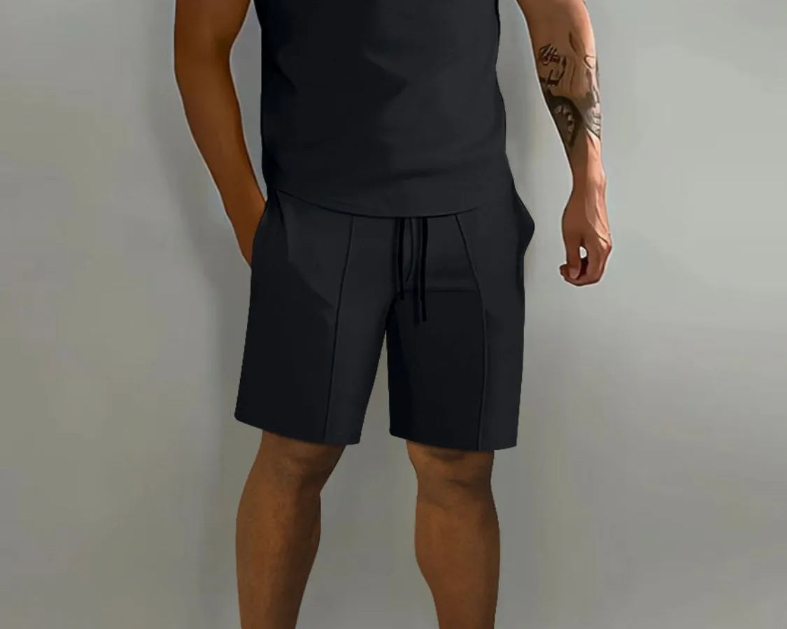 NEWYORKLISTED ATLAS MEN's COLLECTION: Male model wearing a black polo shirt and shorts with white sneakers on a gray background
