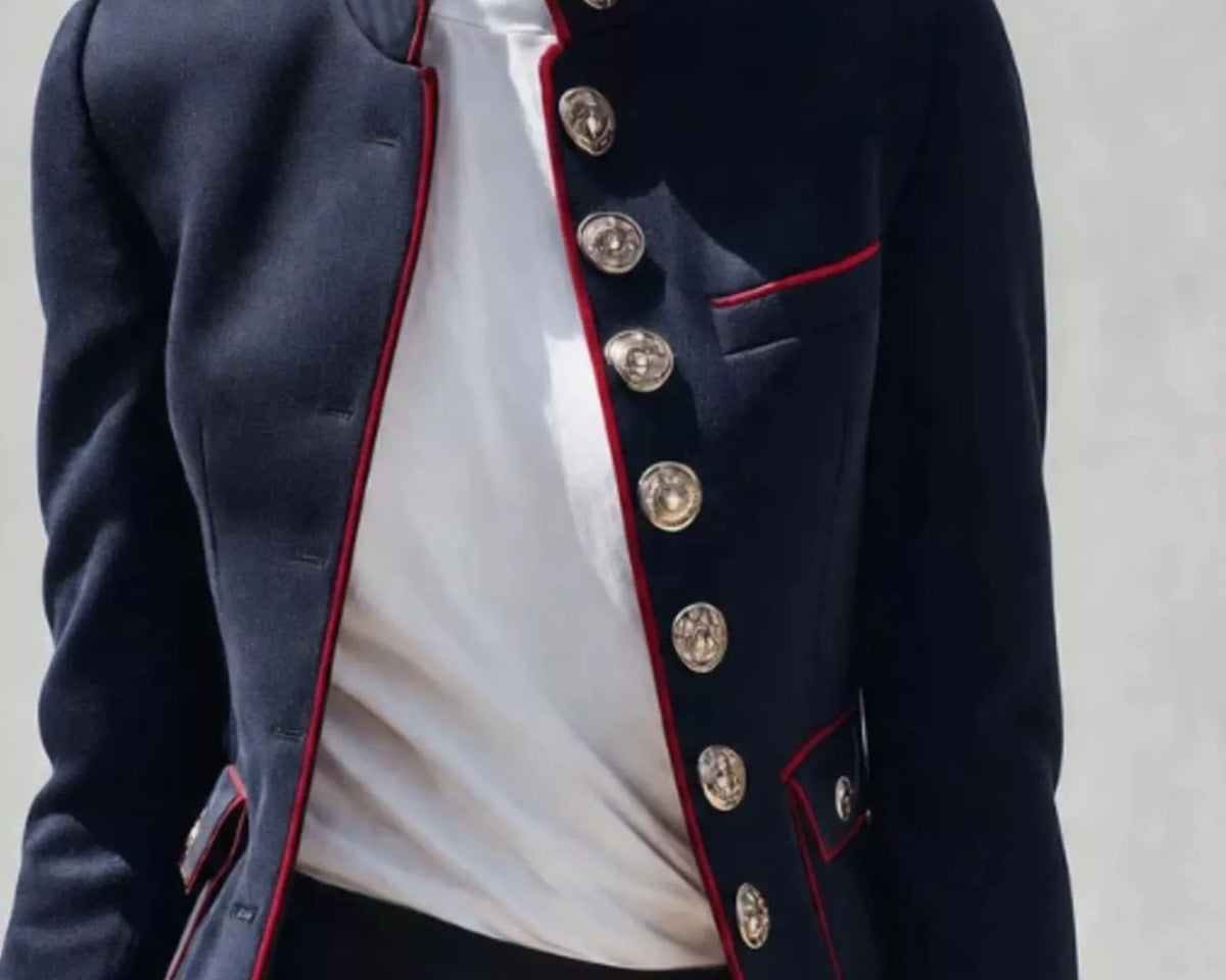 NEWYORKLISTED STYLE COLLECTION: A cropped navy blue military-style blazer with red piping and large silver buttons, worn by a model over a white top and dark skirt.
