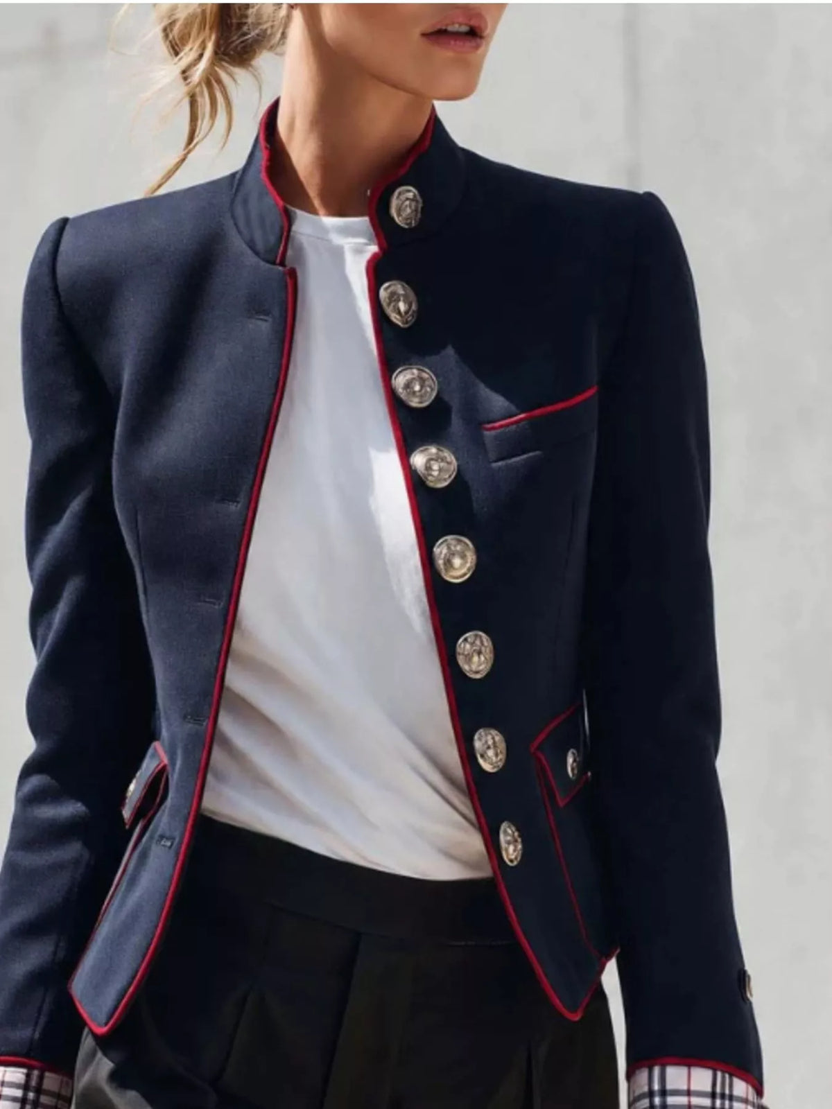 NEWYORKLISTED STYLE COLLECTION: A cropped navy blue military-style blazer with red piping and large silver buttons, worn by a model over a white top and dark skirt.