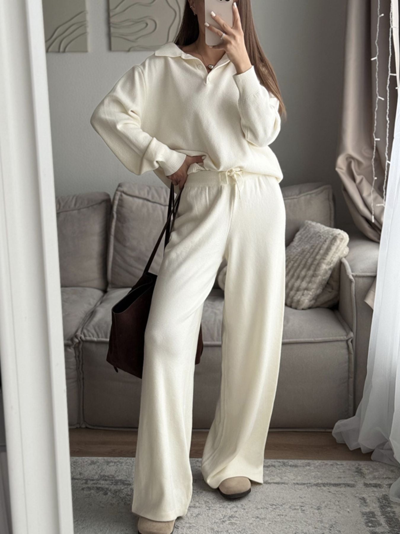 NEWYORKLISTED Comfort Collection: Person wearing a white outfit taking a mirror selfie in a living room.