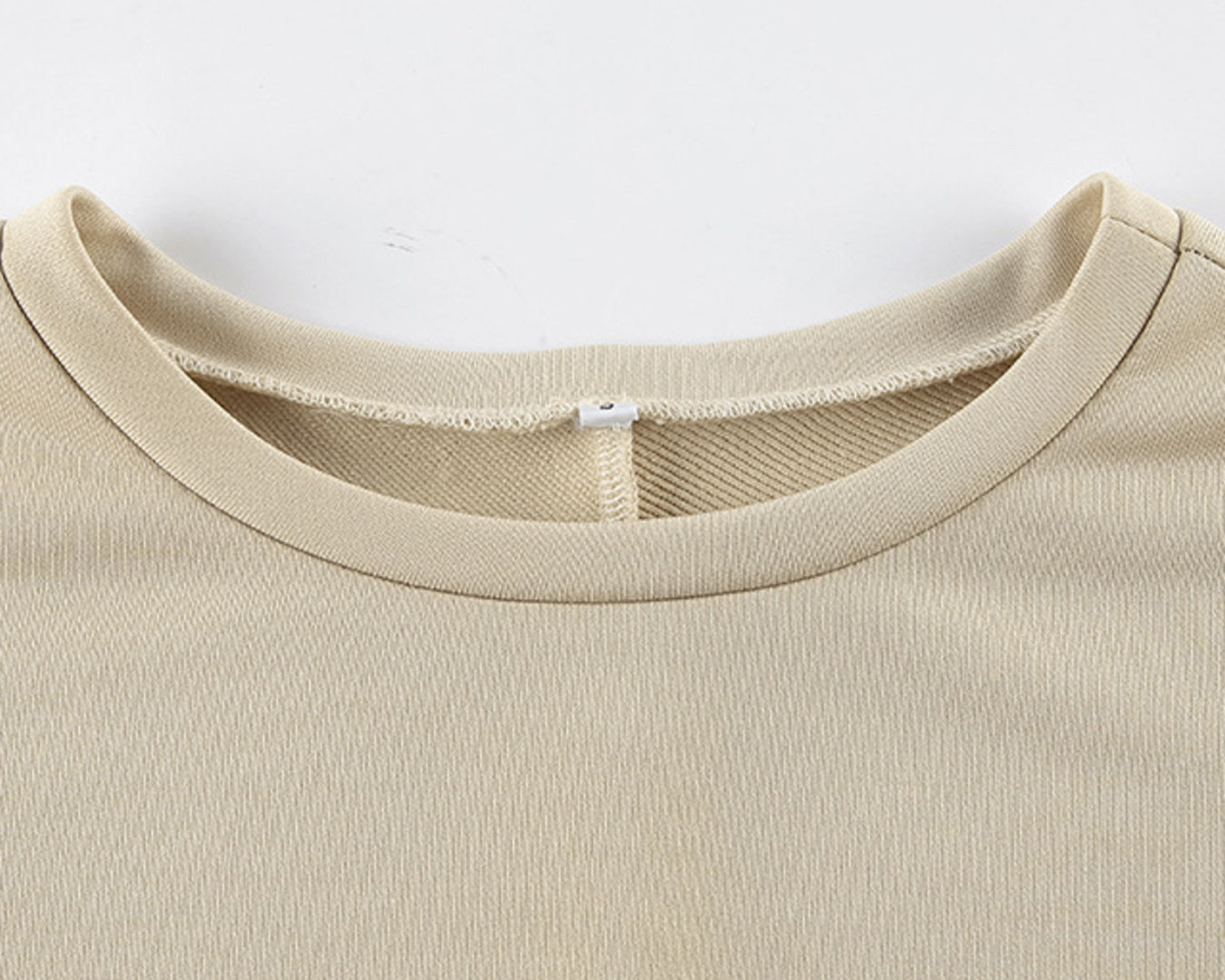 NEWYORKLISTED STYLE COLLECTION: Close-up of a beige t-shirt collar on a white background