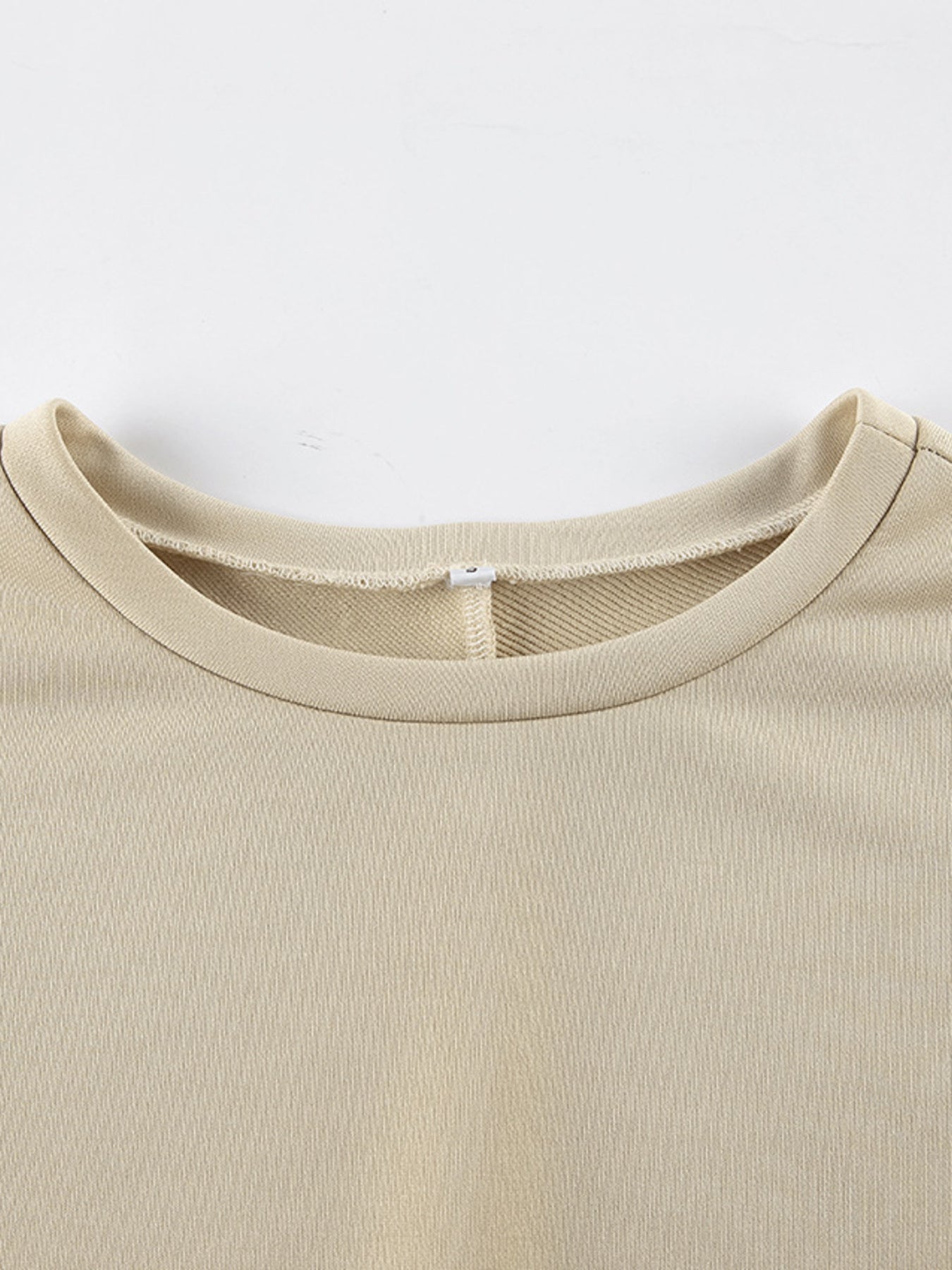 NEWYORKLISTED STYLE COLLECTION: Close-up of a beige t-shirt collar on a white background