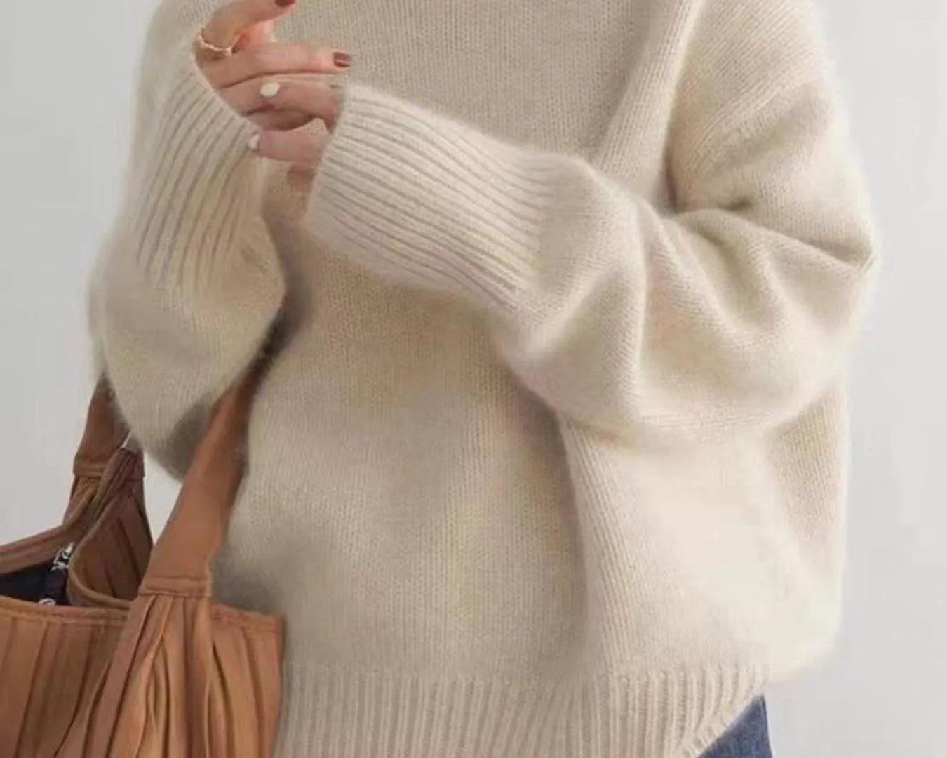 Person wearing a beige sweater with a plain background on NEWYORKLISTED.COM