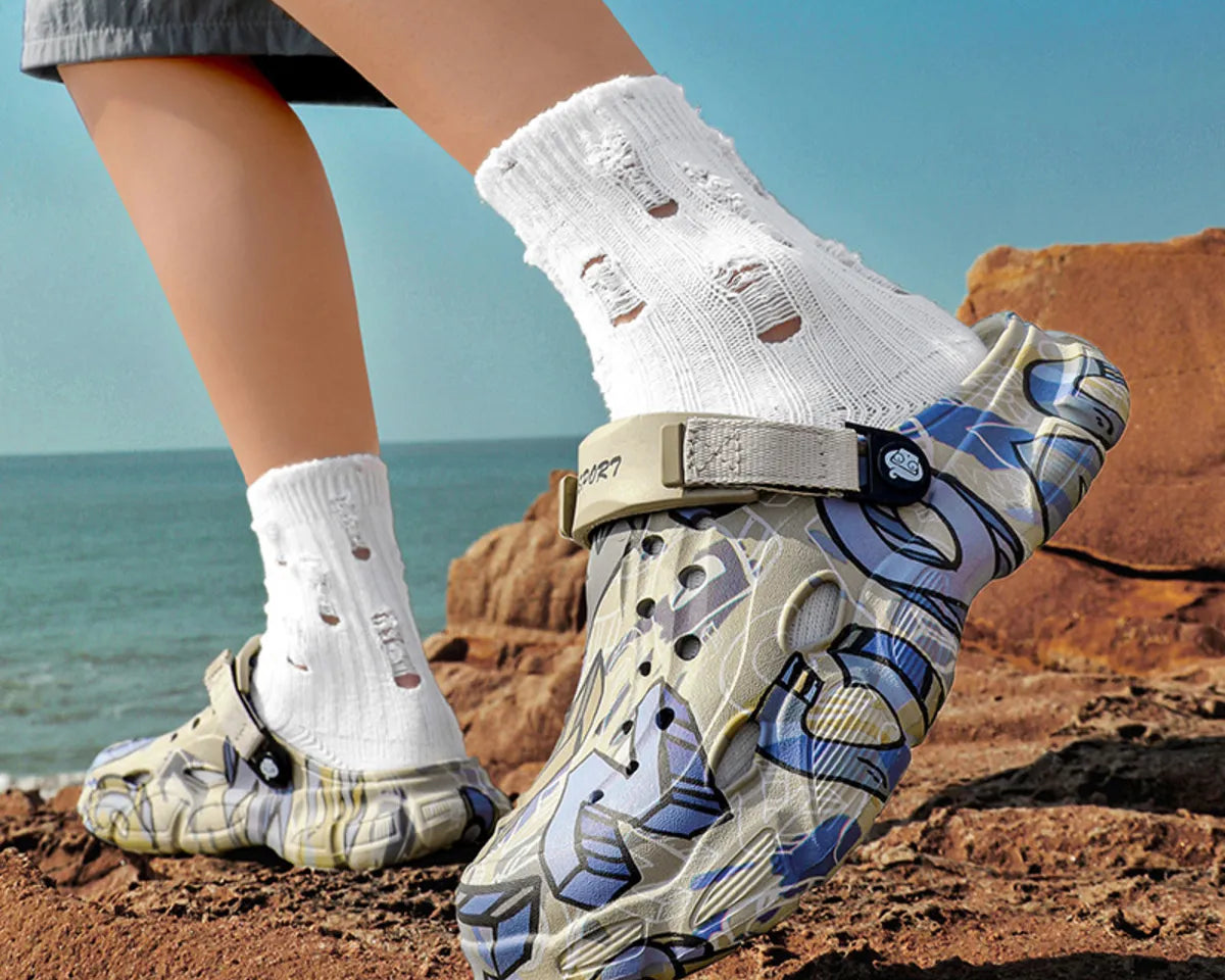 NEWYORKLISTED ATLAS MEN'S COLLECTION: Person wearing patterned shoes and white socks on a rocky beach.