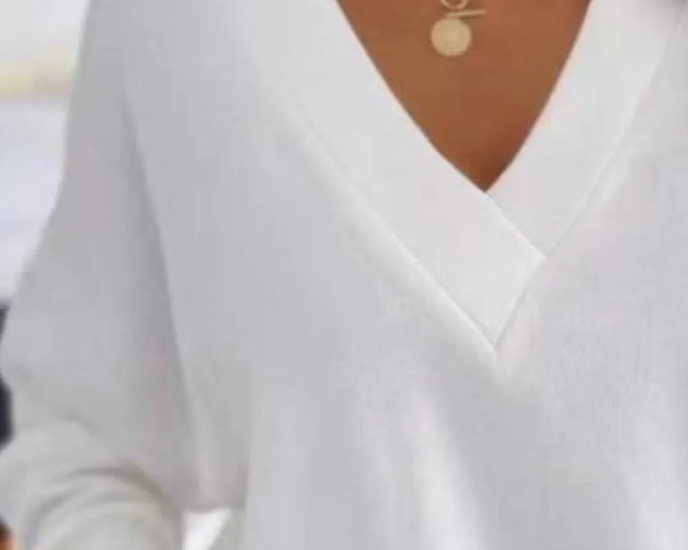 NEWYORKLISTED STYLE COLLECTION: White blouse with a V-neckline worn by a person, with a blurred background