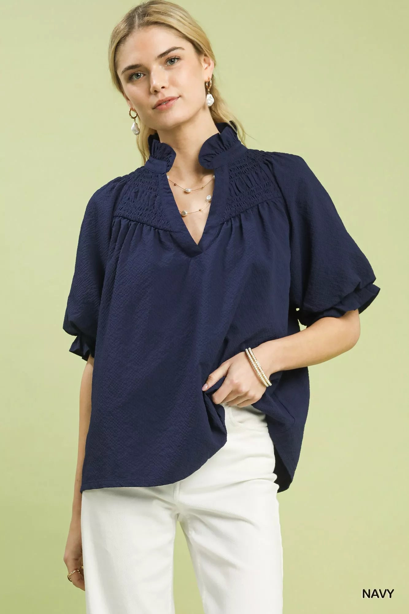 NEWYORKLISTED STYLE COLLECTION: Woman wearing a navy blouse with a green background