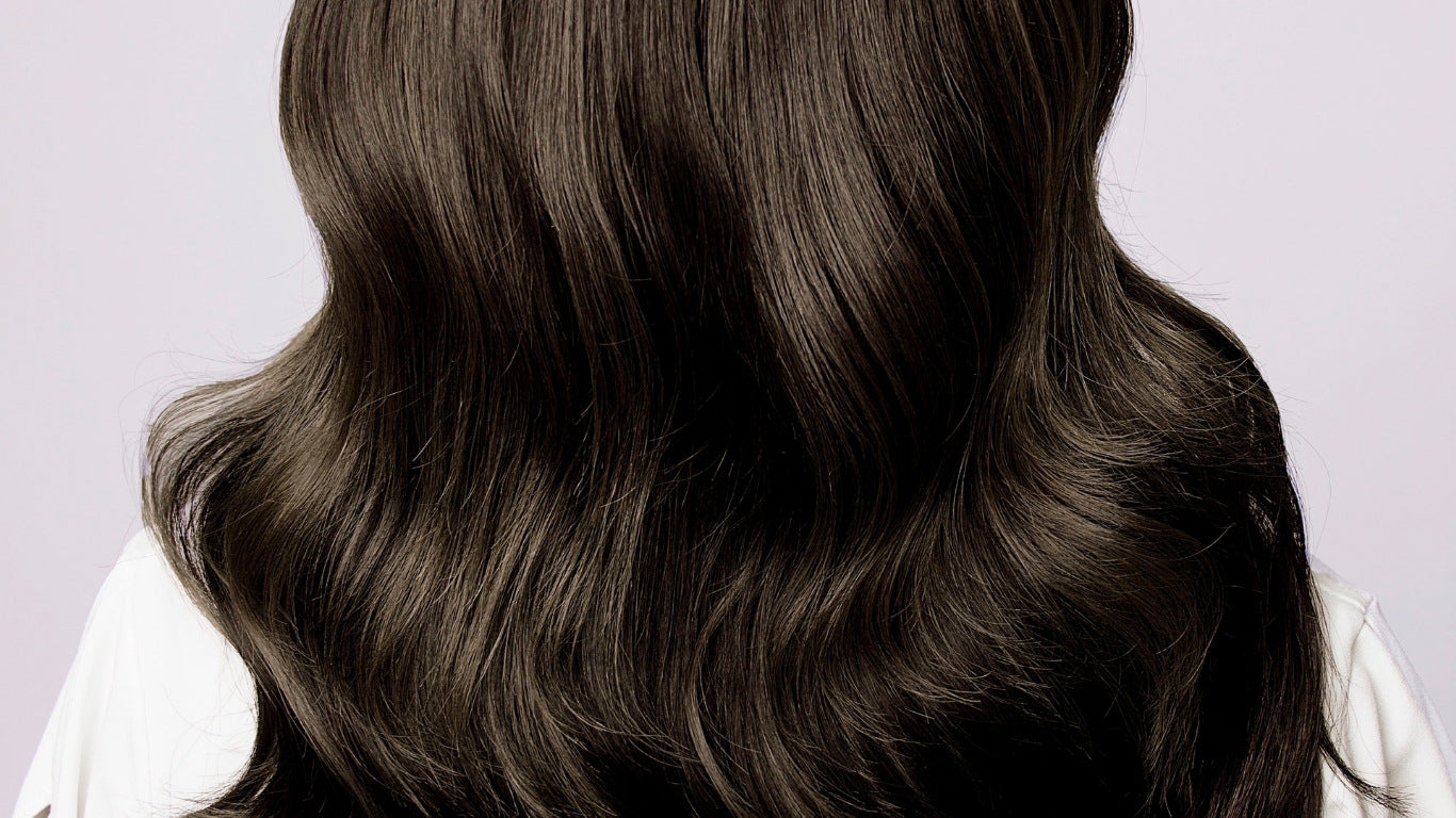 NEWYORKLISTED COSMETIC COLLECTION: Grow Hair Oil, Close-up of long, dark brown hair on a light gray background