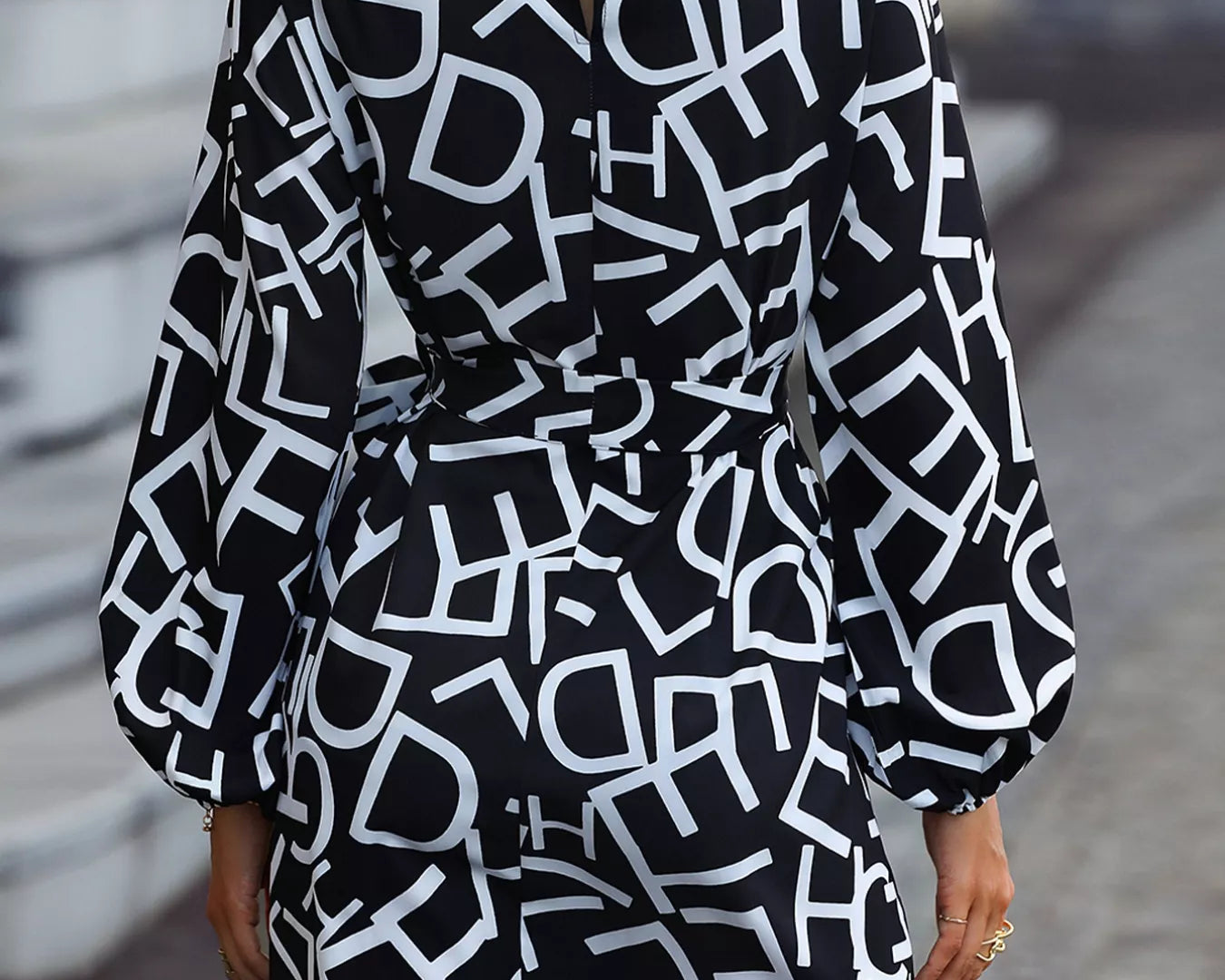 NEWYORKLISTED STYLE COLLECTION: Black dress with white geometric pattern worn by a person on a blurred street background