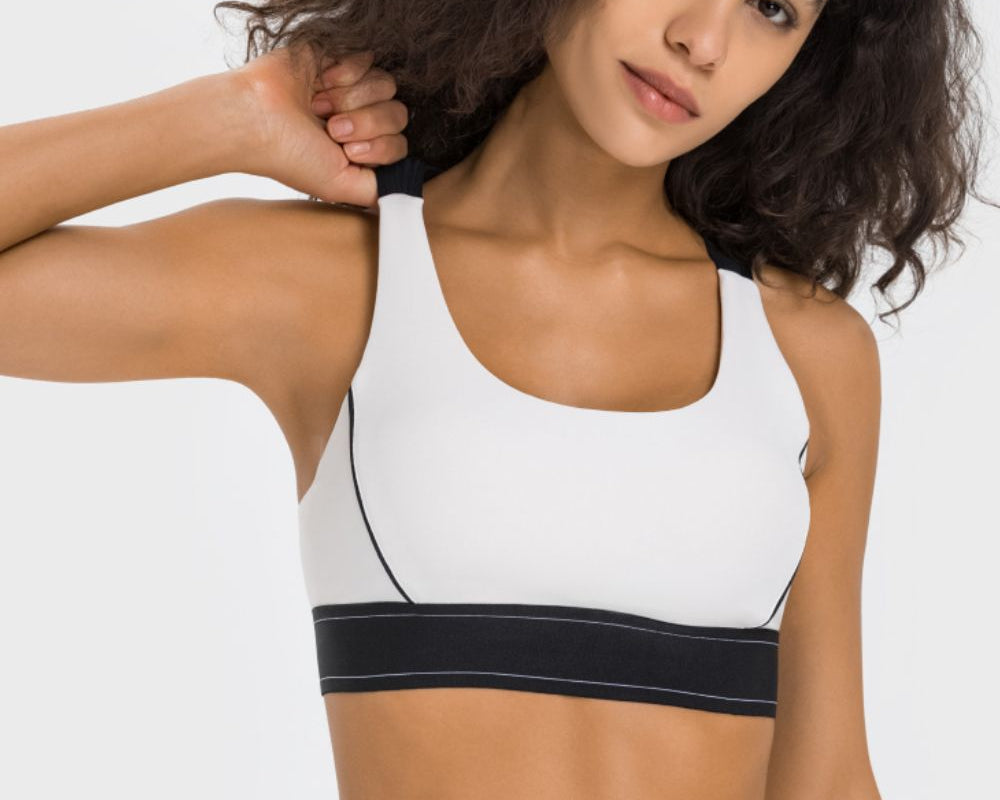 NEWYORKLISTED ACTIVEWEAR COLLECTION: Woman wearing a white sports bra with black accents on a plain background
