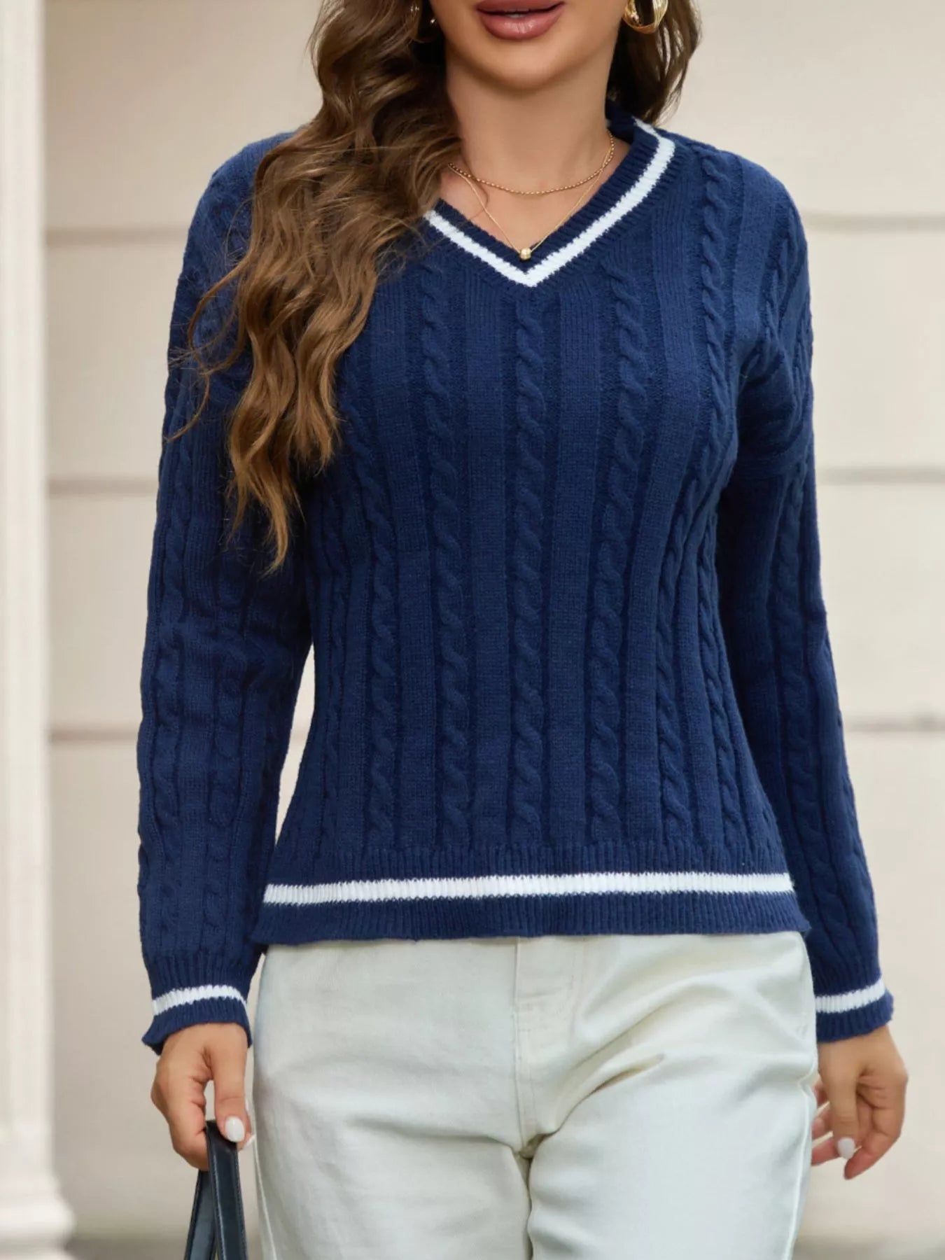 NEWYORKLISTED STYLE COLLECTION: Woman wearing a blue cable knit sweater with white trim.