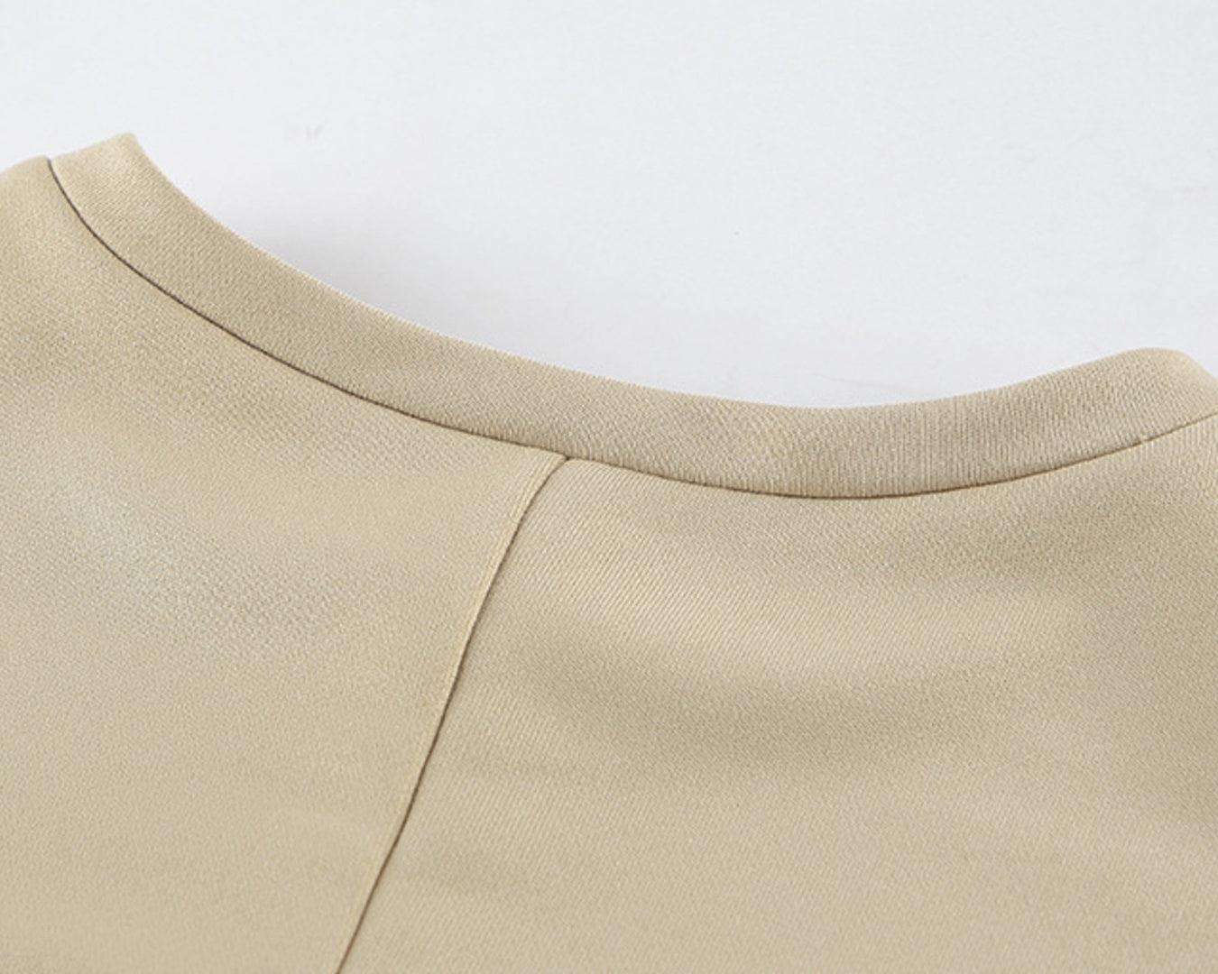 NEWYORKLISTED STYLE COLLECTION: Close-up of a beige garment with a plain background