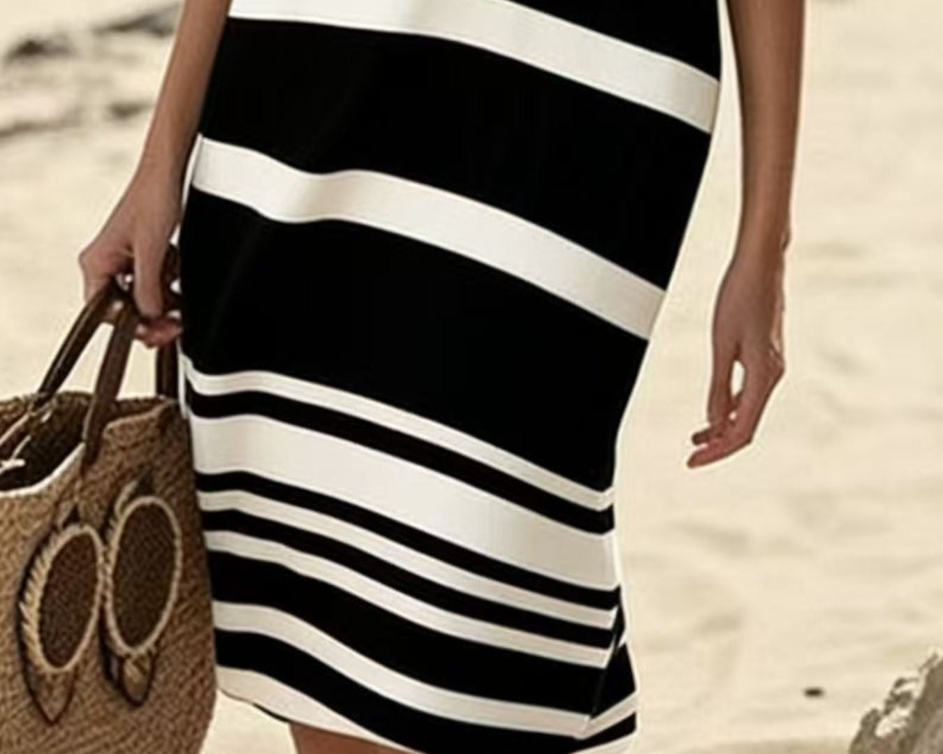 NEWYORKLISTED STYLE COLLECTION: Person wearing a black and white striped dress on a beach.