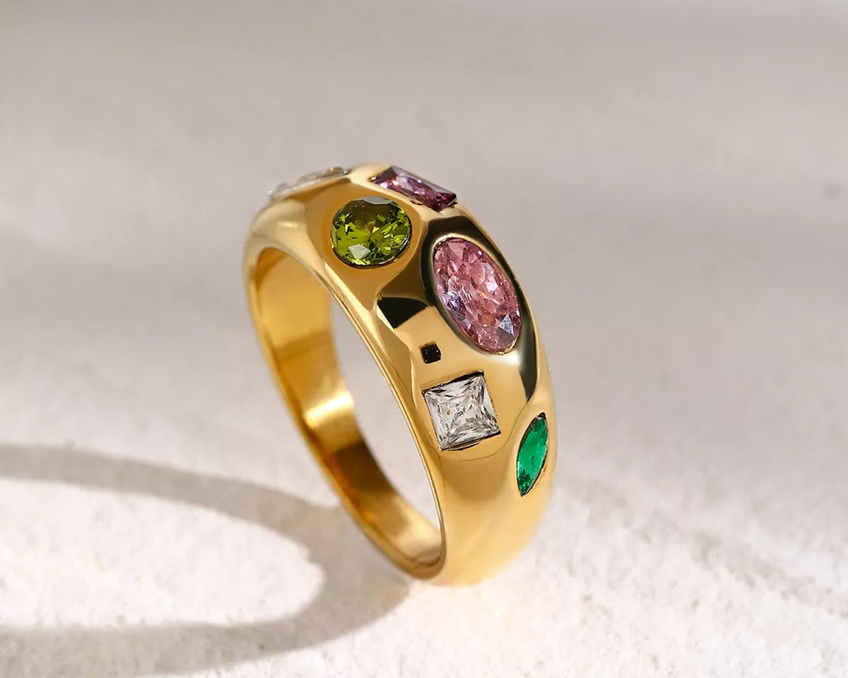 NYLD Glamour Collection by NEWYORKLISTED: Gold ring with multicolored gemstones on a textured white surface