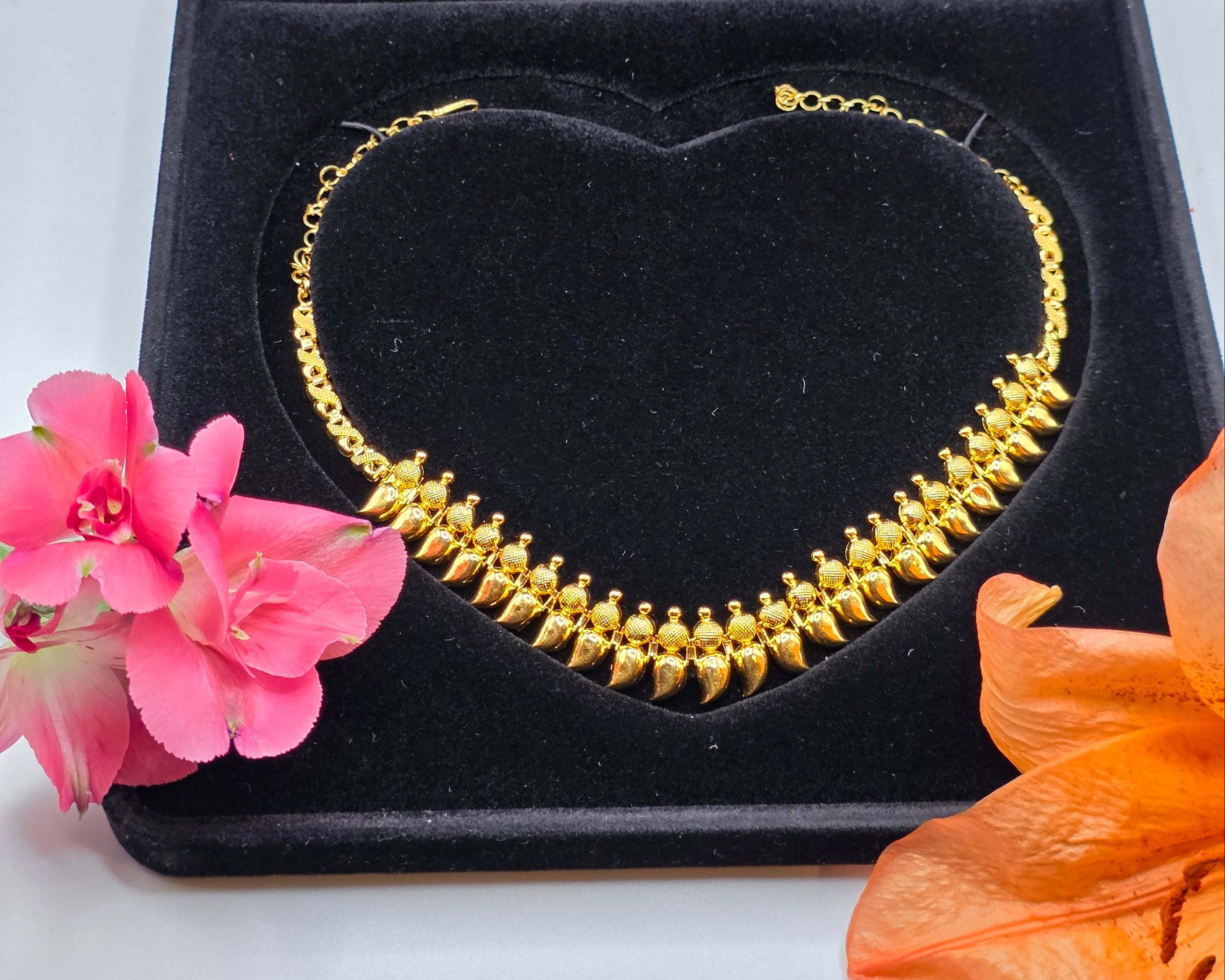 NEWYORKLISTED Valentine's Day Gifts: 22k gold necklace in a black heart-shaped box with flowers on a white background