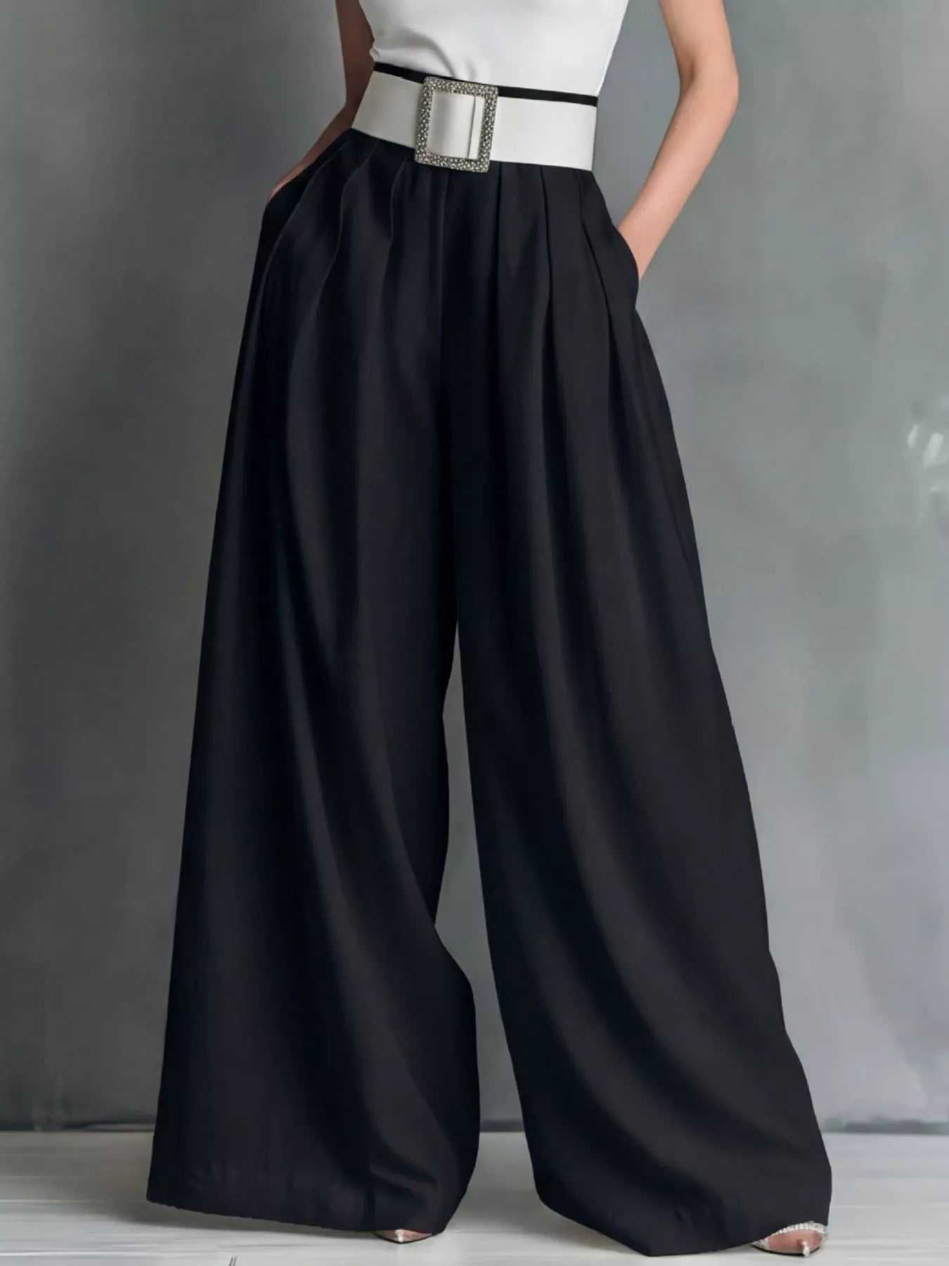 NEWYORKLISTED STYLE COLLECTION: Person wearing a white top and black wide-leg pants with a belt on a gray background
