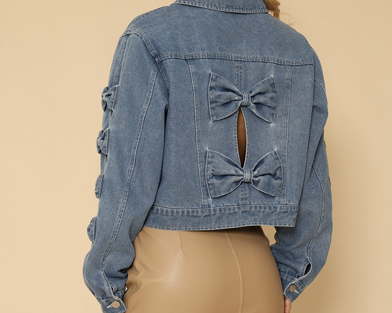 NEWYORKLISTED STYLE COLLECTION: Woman wearing a denim jacket with bow details on a beige background