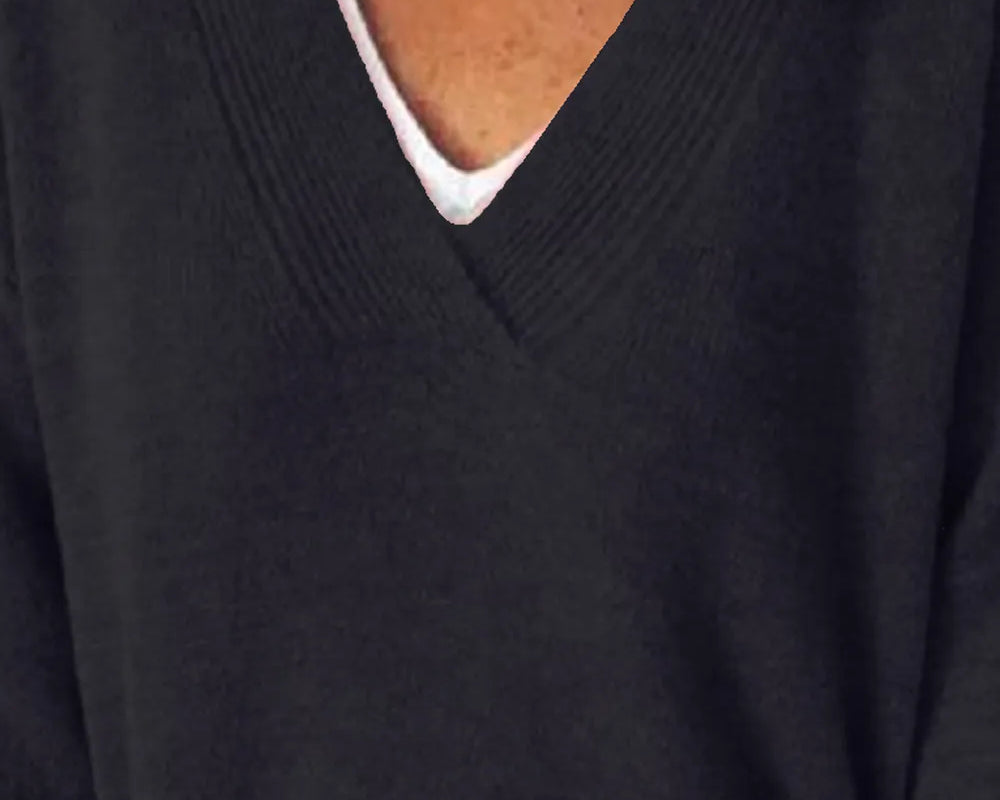 Close-up of a person wearing a dark sweater over a white shirt.