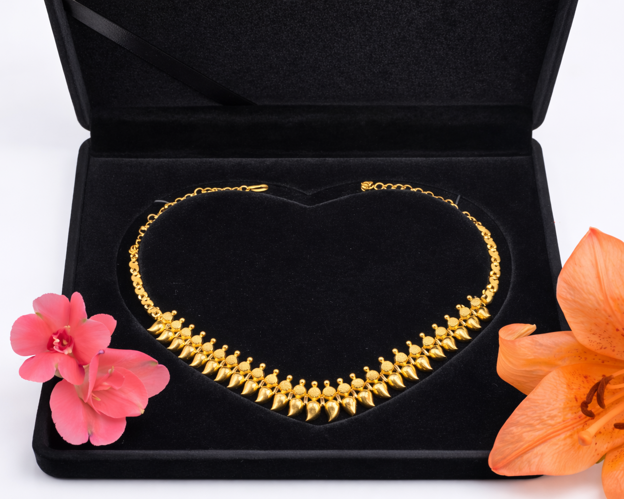 NEWYORKLISTED: 22k gold necklace in a black jewelry box with pink and orange flowers on a white background