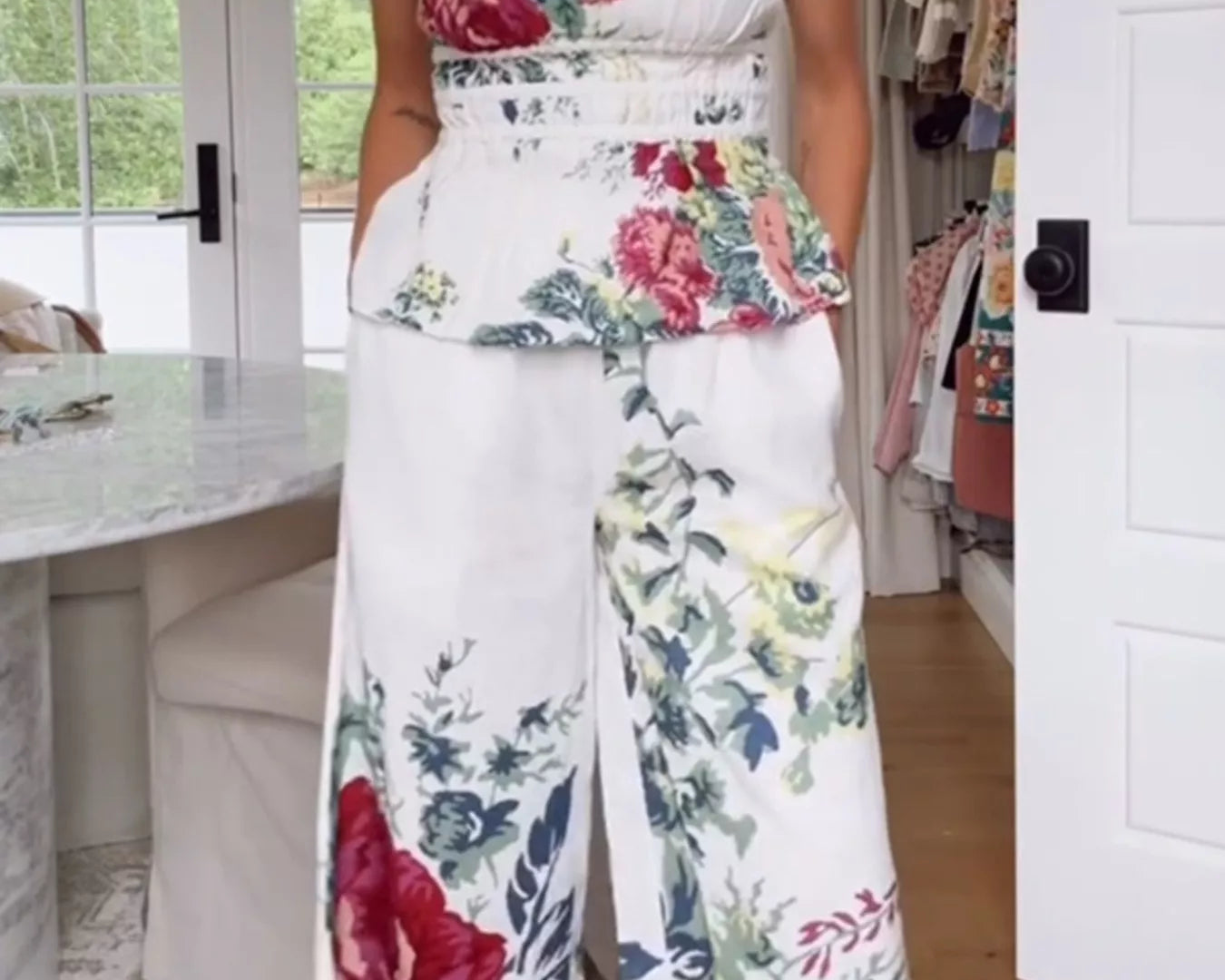 NEWYORKLISTED STYLE COLLECTION: Person wearing a floral strapless top and wide-leg pants in a room with a desk and window.