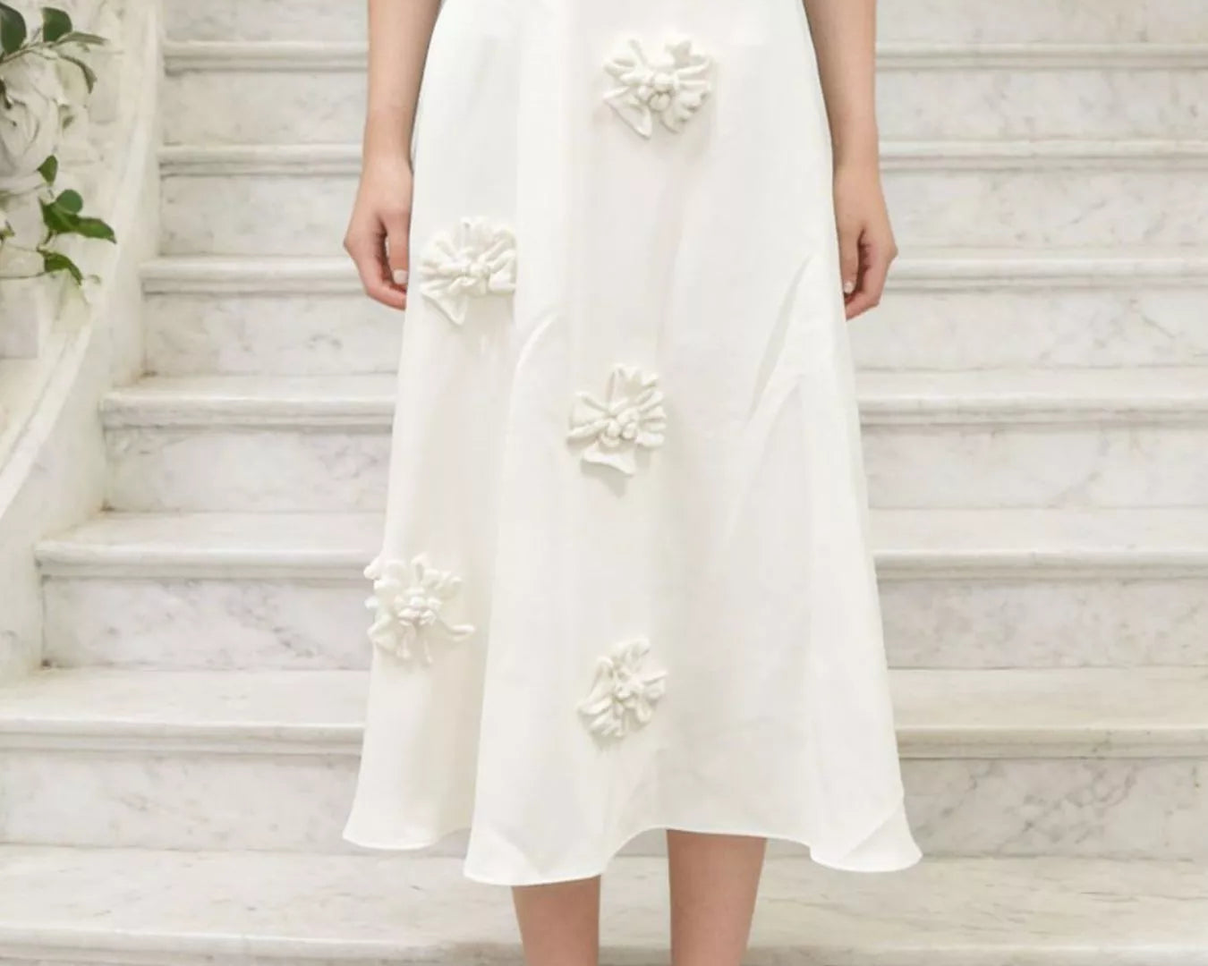 NEWYORKLISTED STYLE COLLECTION: Person wearing a white floral skirt on a marble staircase