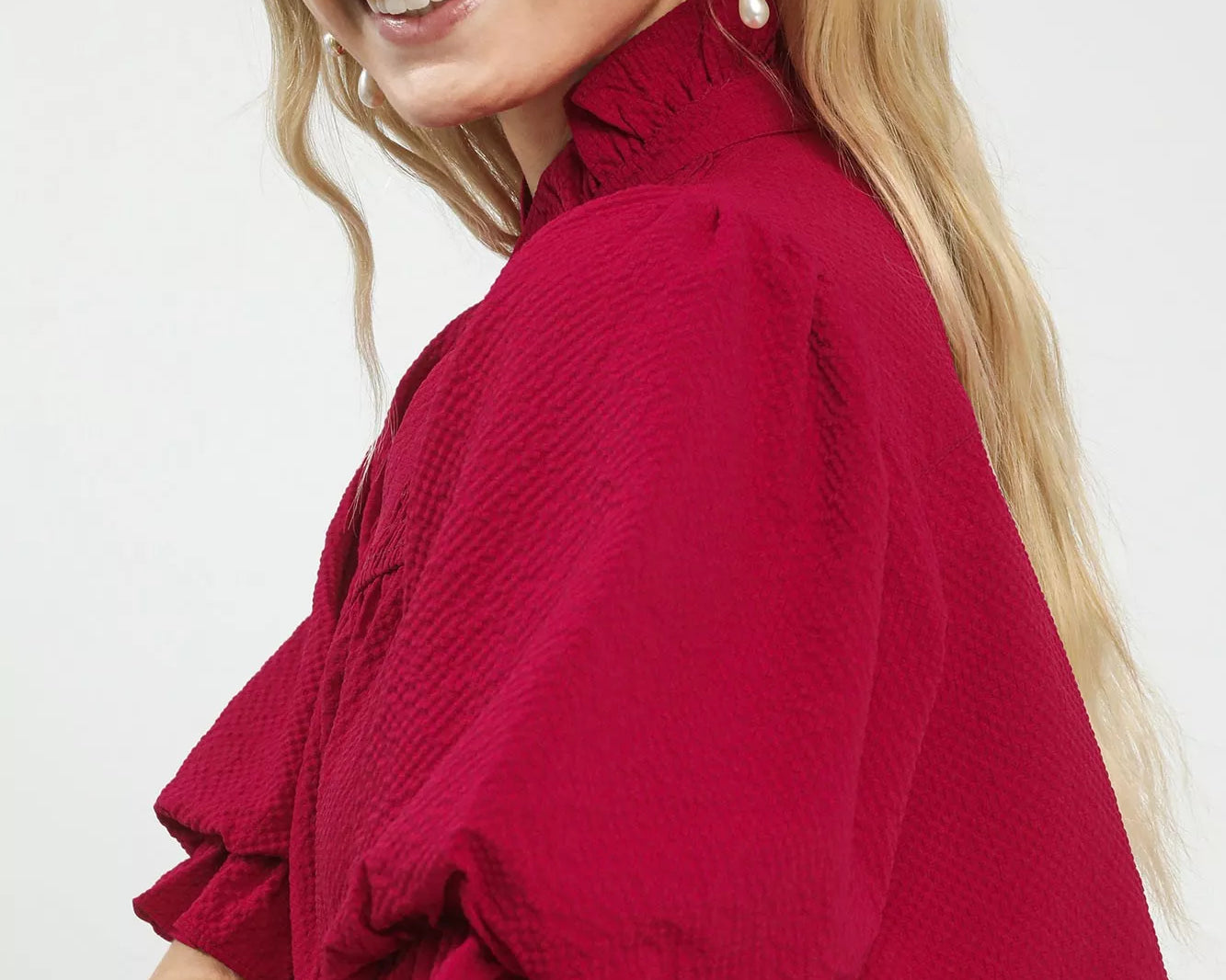 NEWYORKLISTED Style Collection: Woman wearing a red blouse with ruffled sleeves on a white background