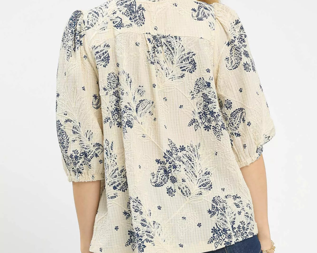 NEWYORKLISTED STYLE COLLECTION: Woman wearing a cream blouse with navy floral pattern and blue jeans on a white background