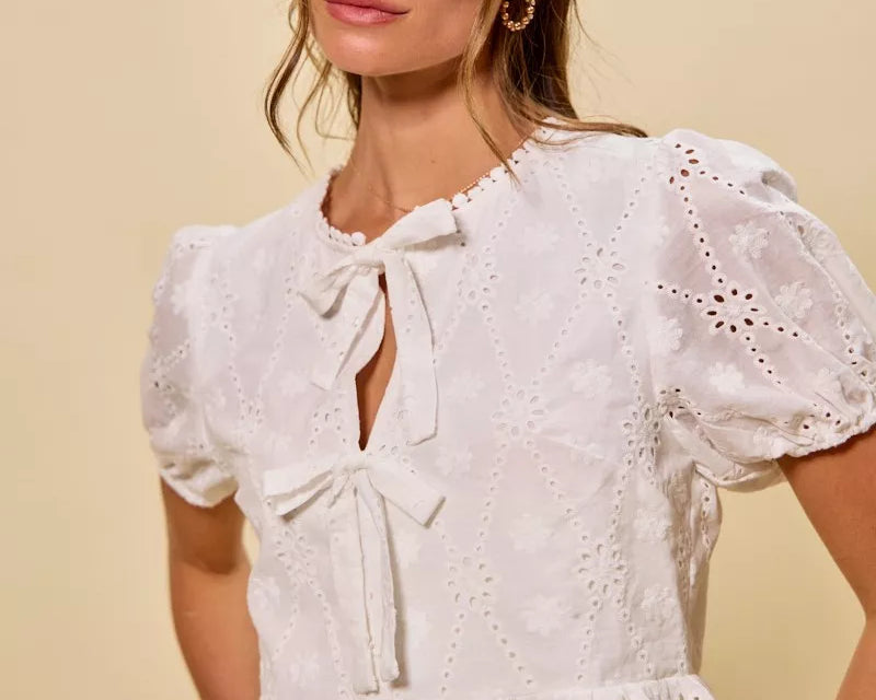 NEWYORKLISTED STYLE COLLECTION: Woman wearing a white lace blouse with puff sleeves against a beige background