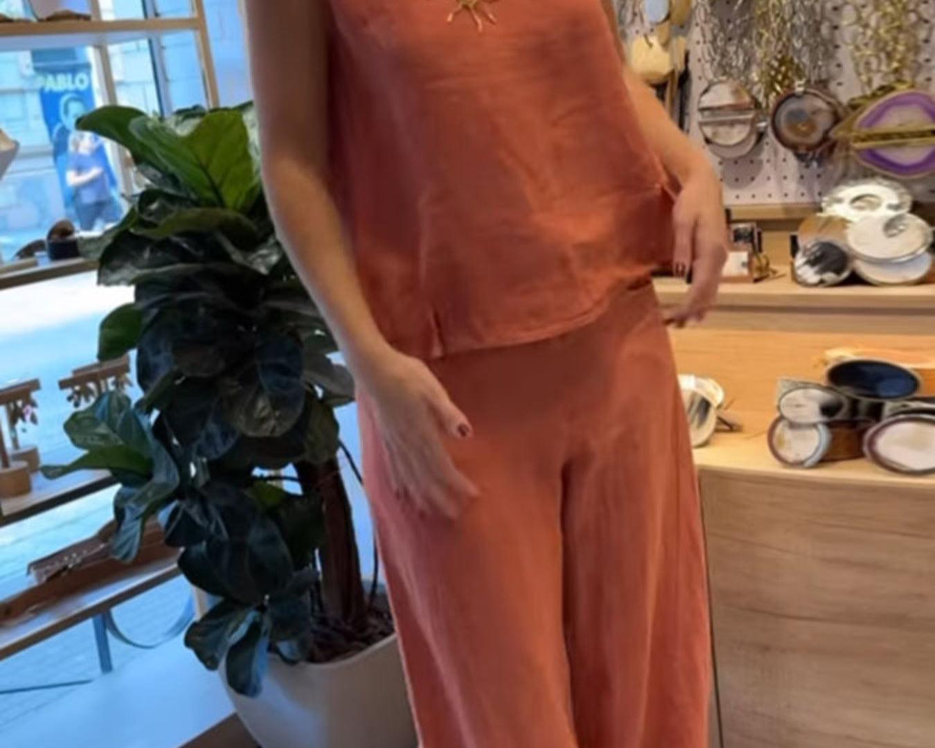 NEWYORKLISTED COMFORT COLLECTION: Person wearing an orange outfit in a store setting with decor and plants.