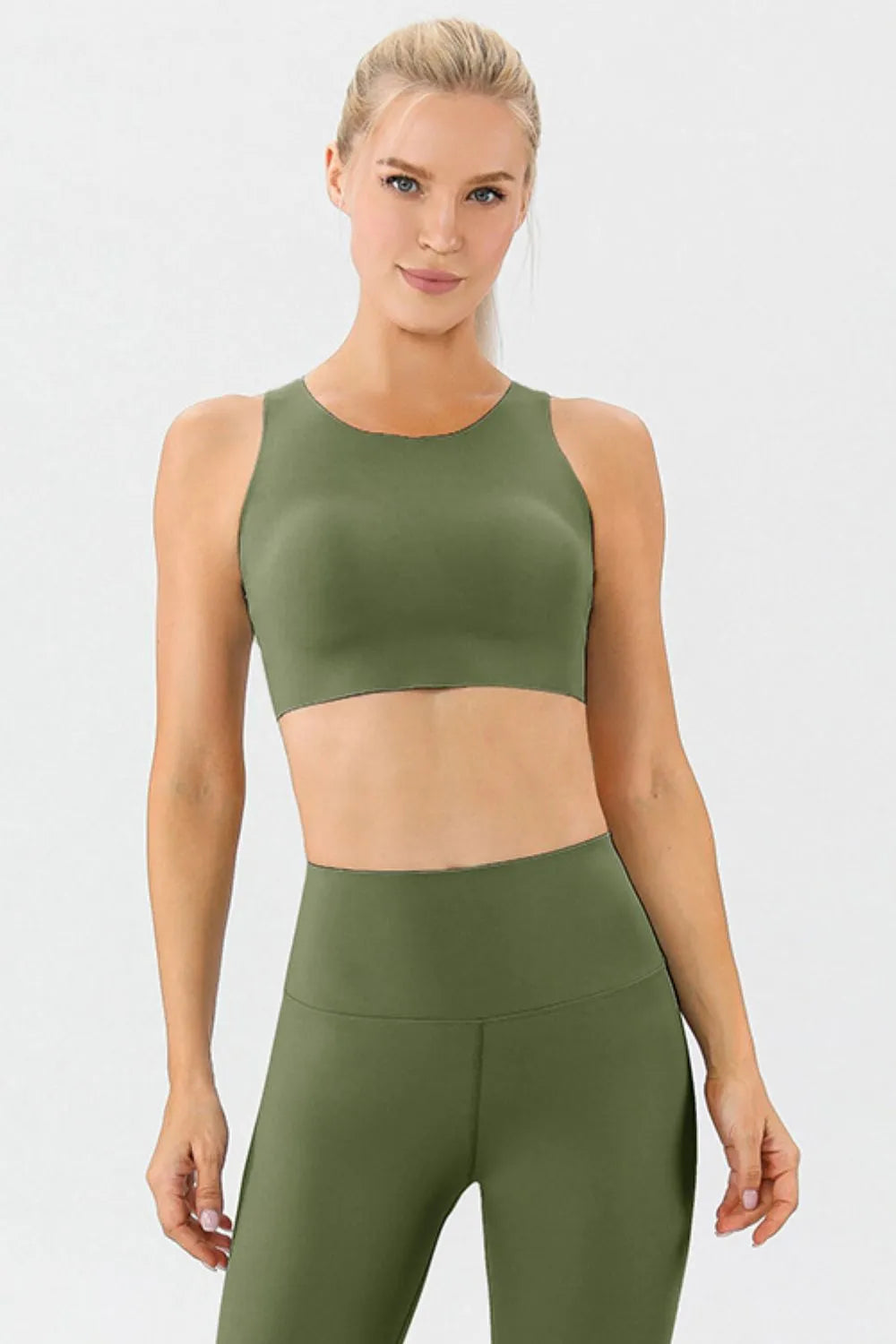 NEWYORKLISTED ACTIVEWEAR COLLECTION: Woman wearing an olive green sports bra and leggings set on a white background