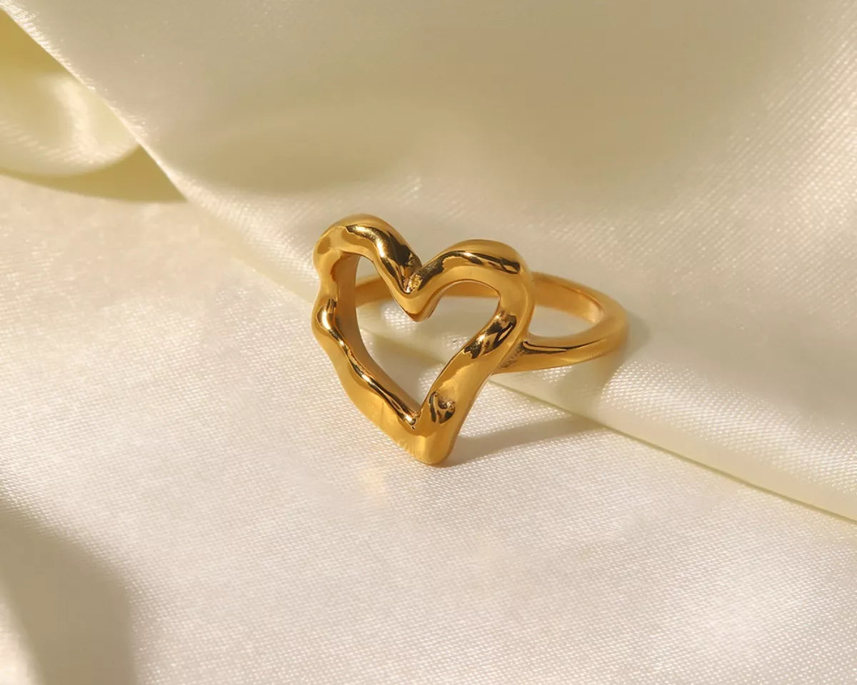NYLD Glamour Collection by NEWYORKLISTED: Gold heart-shaped ring on a soft beige fabric background