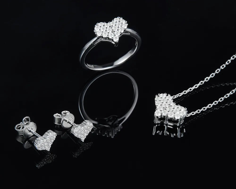 NYLD Glamour Collection By NEWYORKLISTED: Silver jewelry set including earrings, a ring, and a necklace on a black background