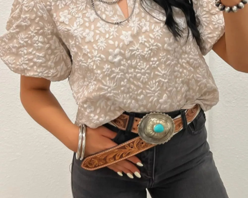NEWYORKLISTED STYLE COLLECTION: Woman taking a mirror selfie wearing a patterned blouse and dark jeans with a belt.