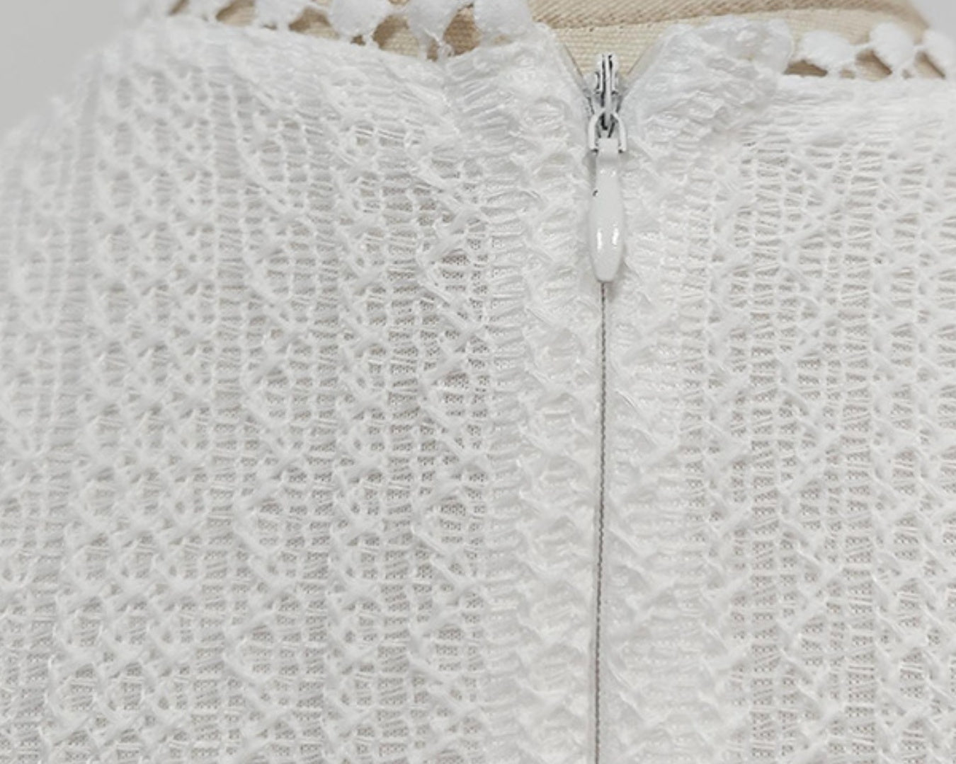 NEWYORKLISTED STYLE COLLECTION: Close-up of a textured white garment with a zipper on a mannequin.