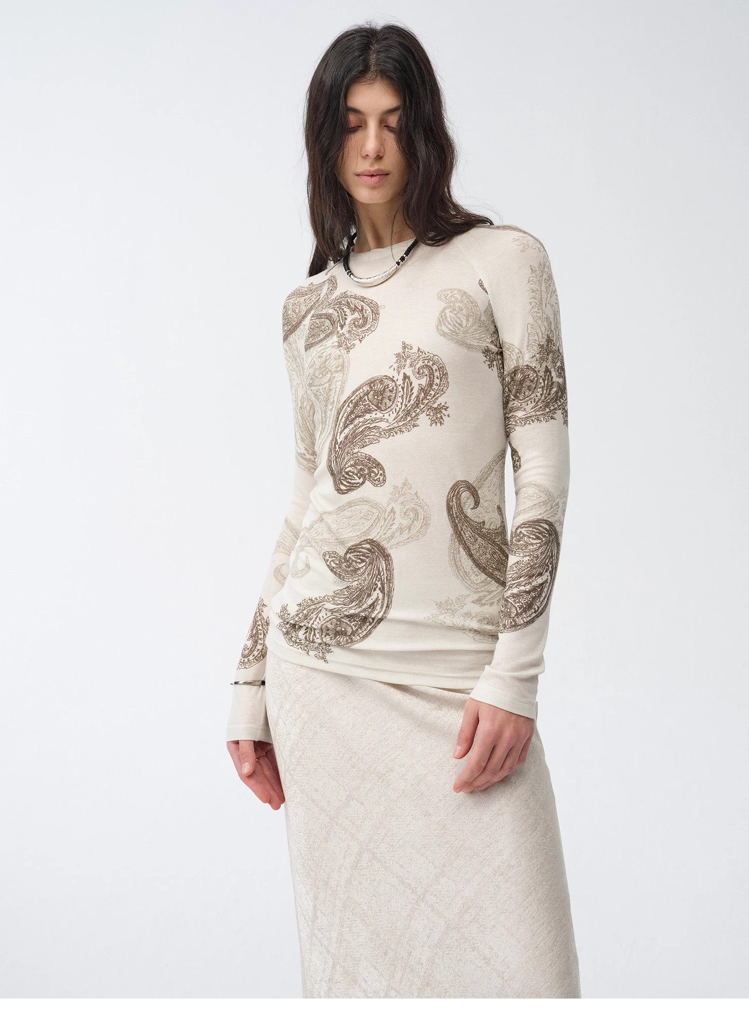Woman wearing a long-sleeve top with paisley patterns on a white background