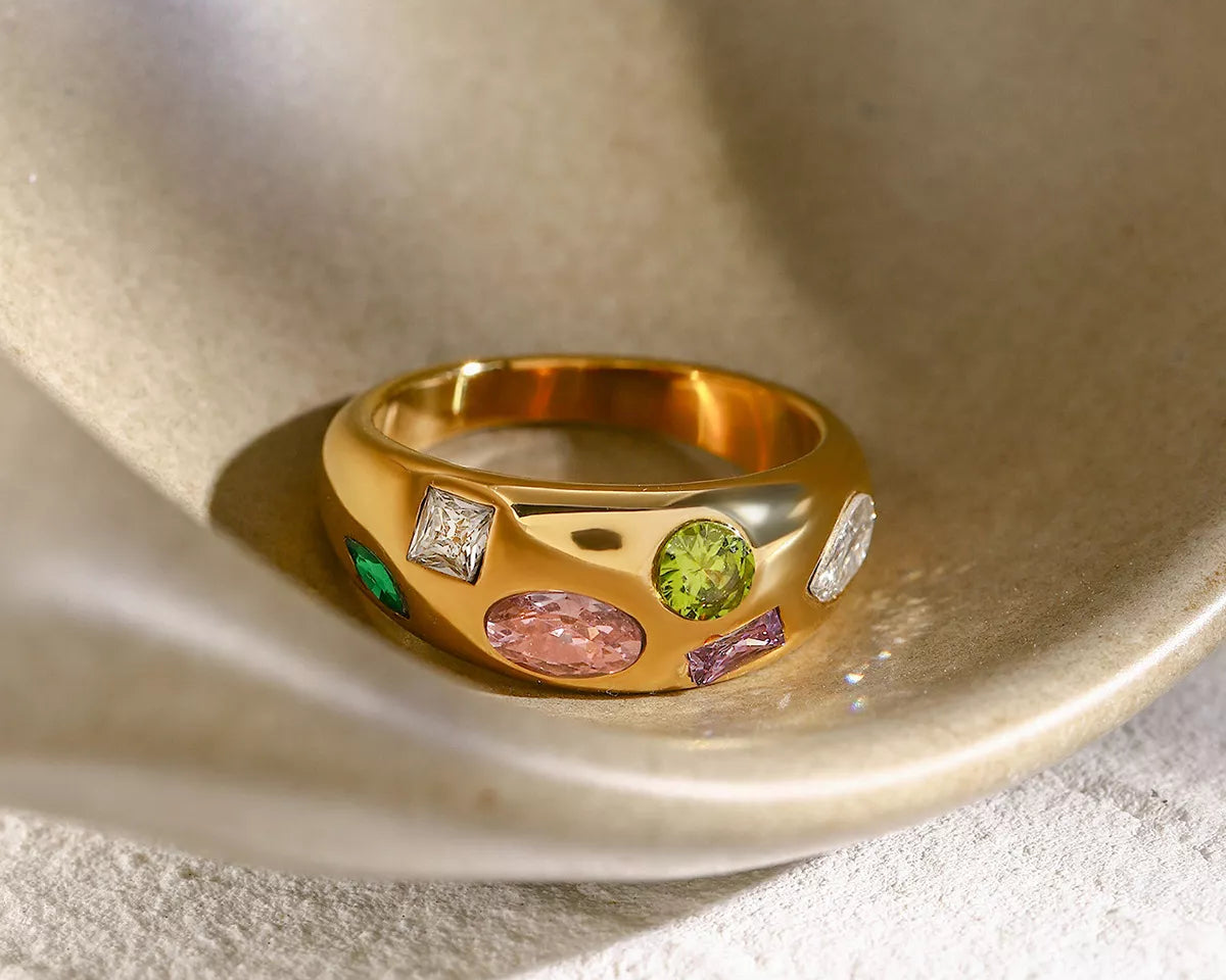NYLD Glamour Collection by NEWYORKLISTED: Gold ring with colorful gemstones on a textured surface