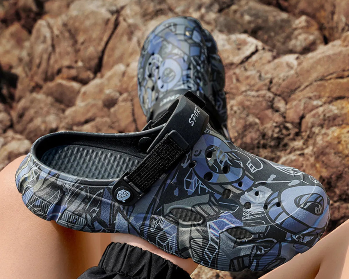 NEWYORKLISTED ATLAS MEN'S COLLECTION: Clogs with a blue and gray pattern worn by a person sitting on rocks.
